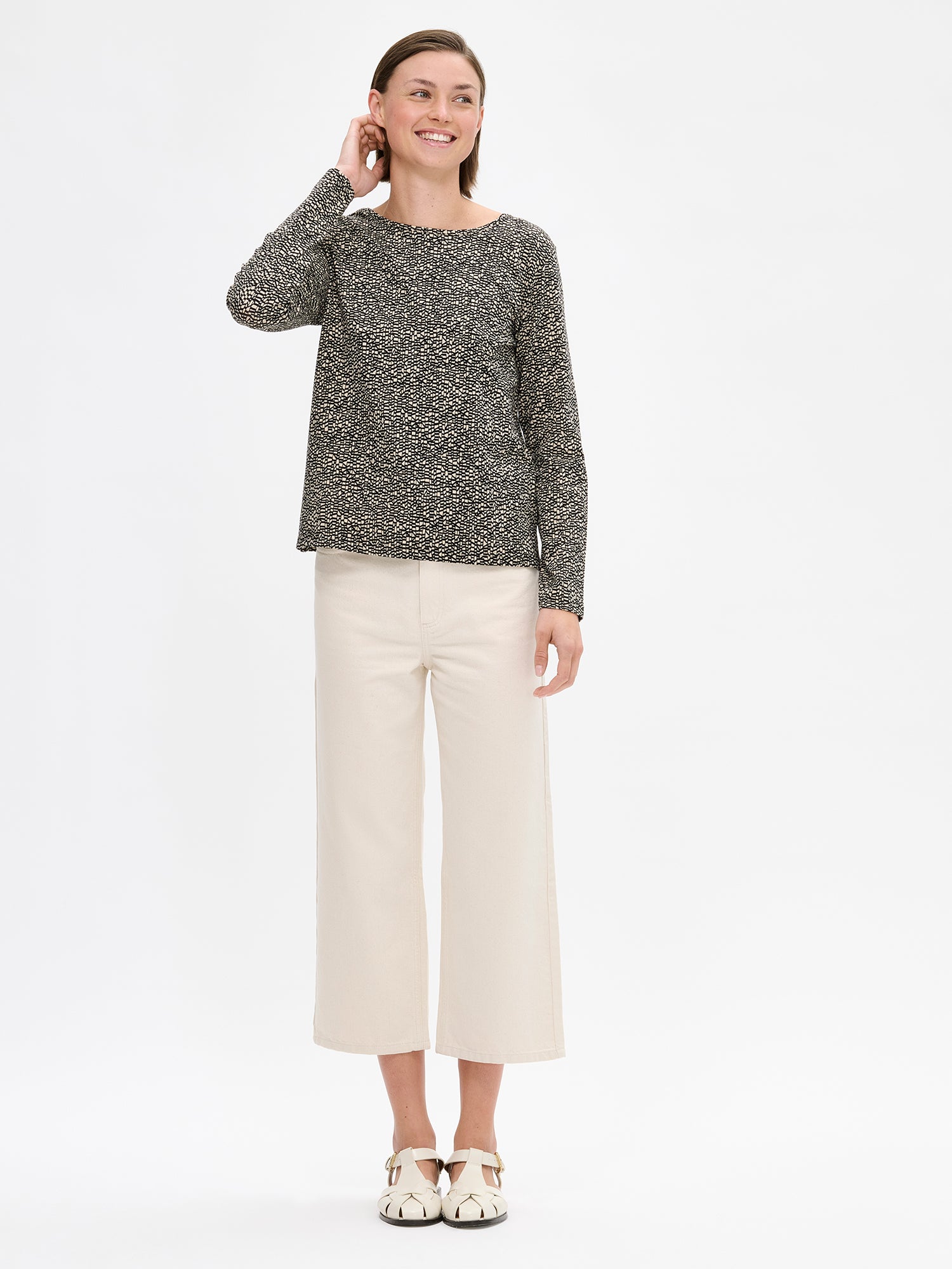 Nanso women's patterned Kaislat blouse in beige with a round neckline and full-length sleeves. On a model with wide off white jeans.