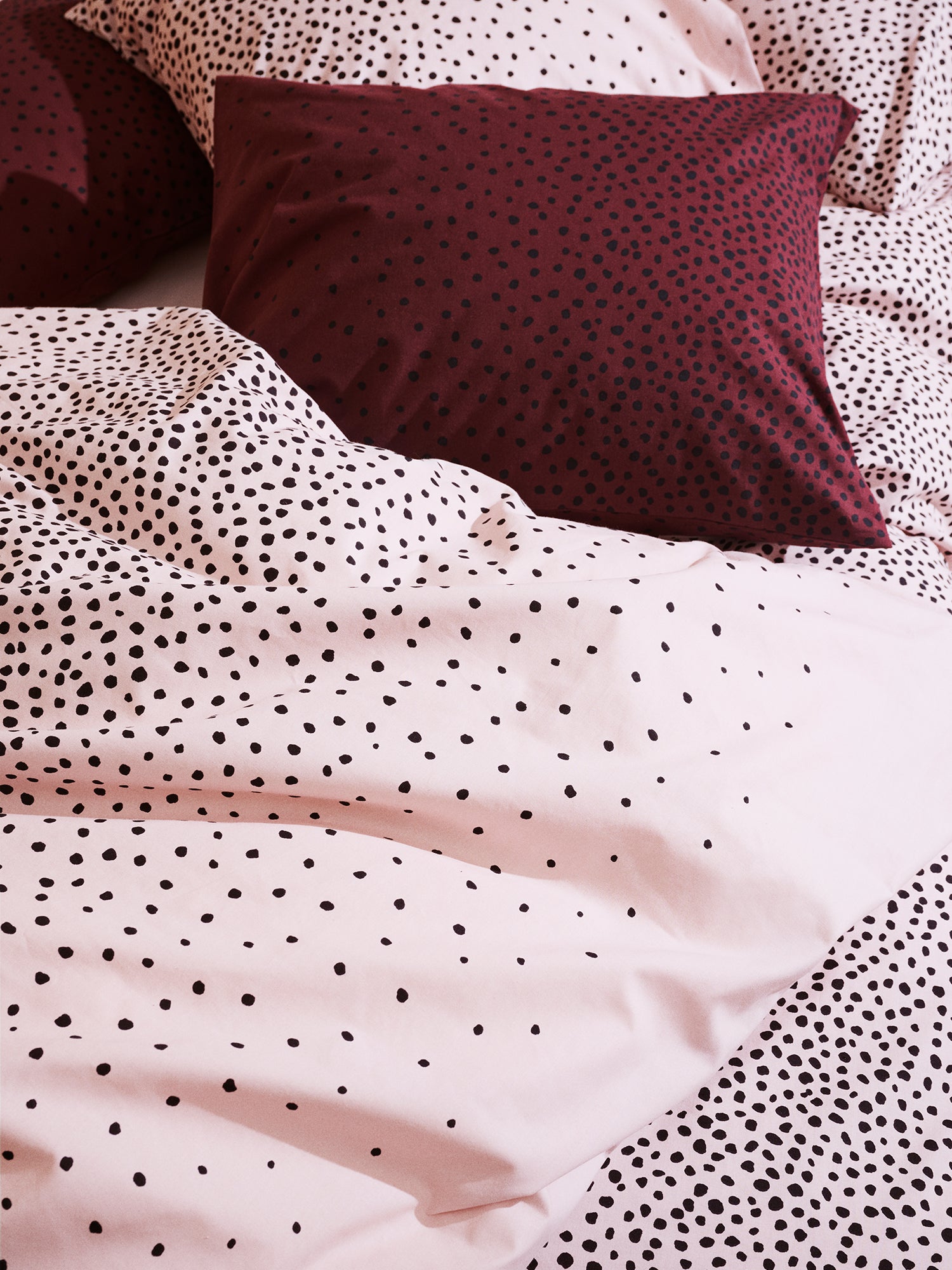 Brown Täplä pillow cases with rose Täplä duvet cover on a bed.