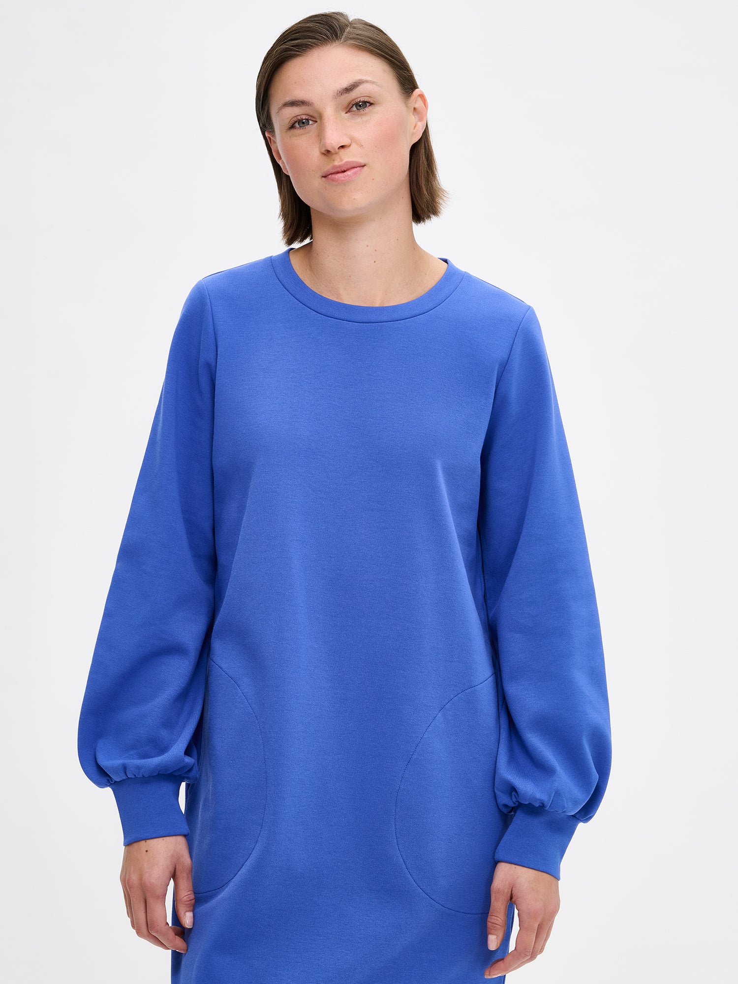 Nanso women's blue Leija-dress. This straight-cut dress features a round neckline, side pockets, and full-length sleeves that gather beautifully at the cuffs. On a model, close-up.