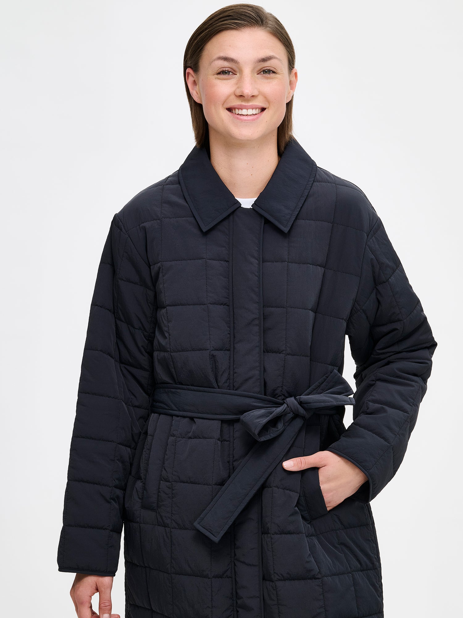Nanso Marje Quilted Coat features classic collar styling and convenient snap closures at the front, a belt for a personalized fit, and practical front patch pockets. on a model, close-up.
