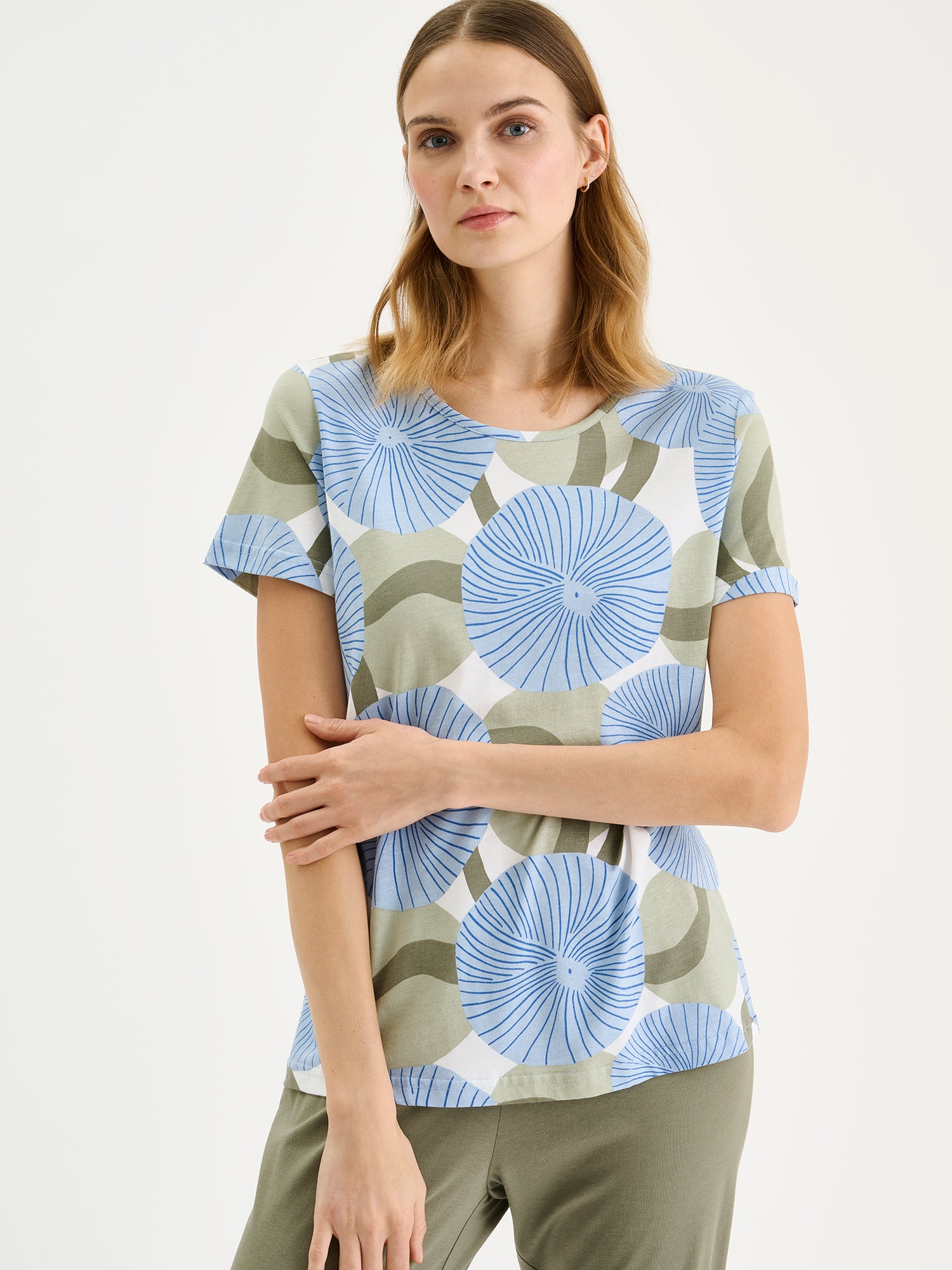 Soft and stylish, the HEDDA Pajamas feature a delicate blue-toned print on the short-sleeved top paired with olive-green bottoms. Pictured on a model, close-up.