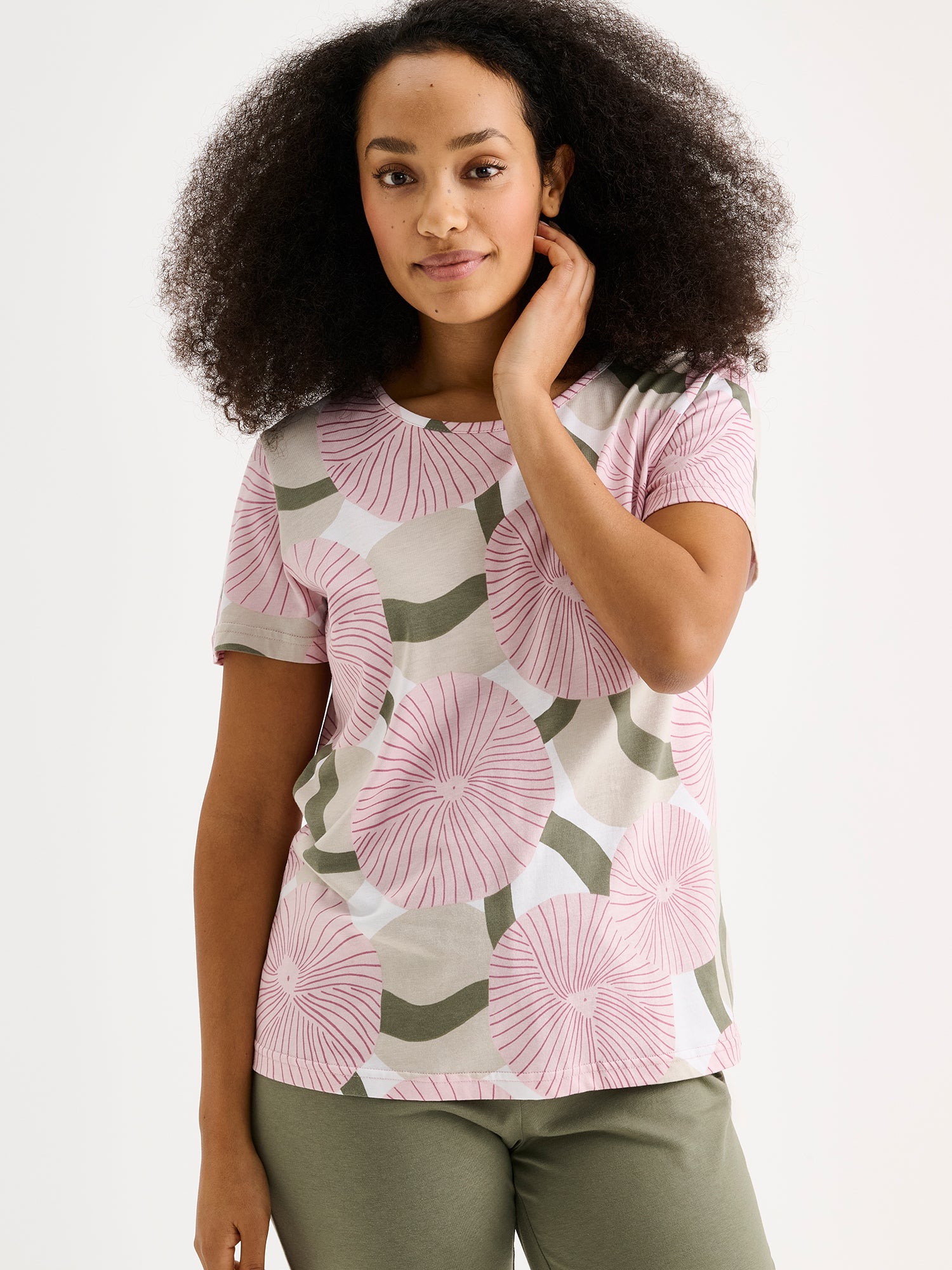Soft and stylish, the HEDDA Pajamas feature a delicate pink-toned print on the short-sleeved top paired with olive-green bottoms. Pictured on a model, close-up.