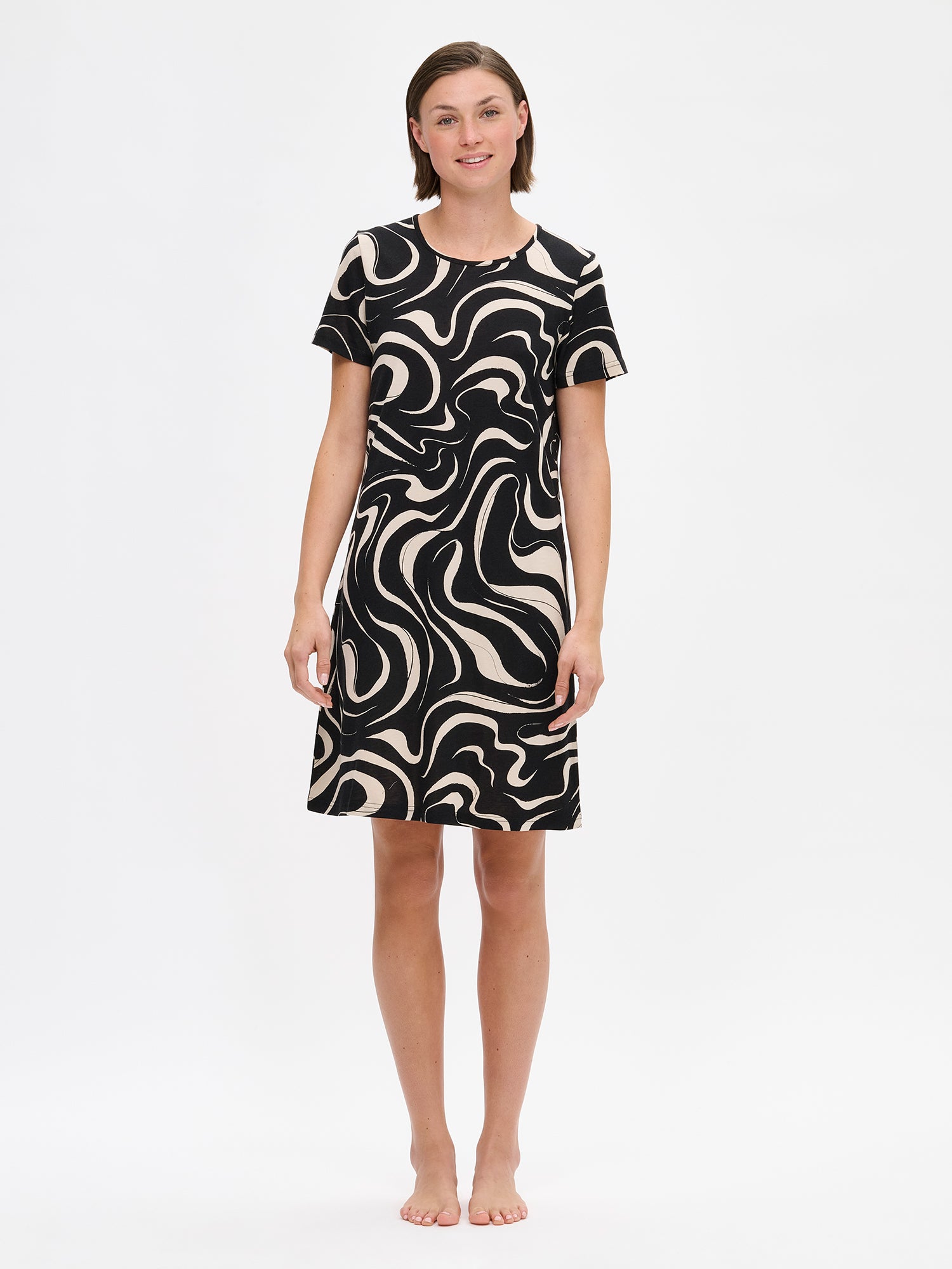 Nanso VESI short nightgown in black and beige tones with an elegant patterned design. Features a classic round neckline and relaxed fit and soft material for restful nights. On a model from the front.