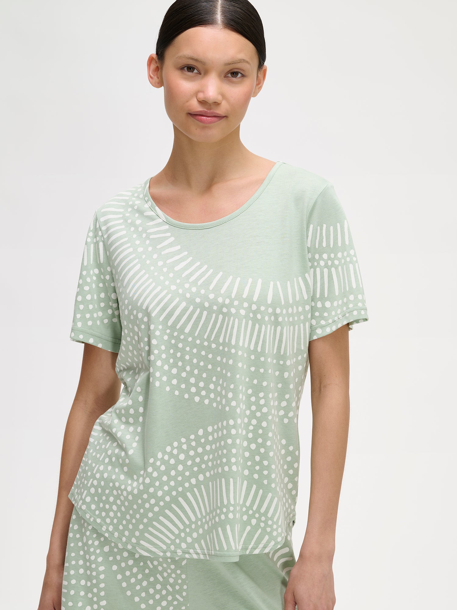 Nanso comfortable light green Aura shorts pyjamas featuring a stylish, harmonious pattern on a model with dark hair, close-up.