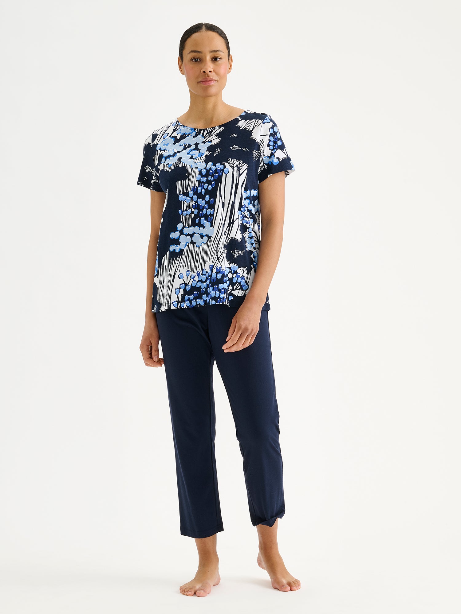 Nanso KIRJOKERTTU Pajamas, featuring a short-sleeved top with an elegant nature-inspired blue pattern paired with solid dark blue pants on a model.