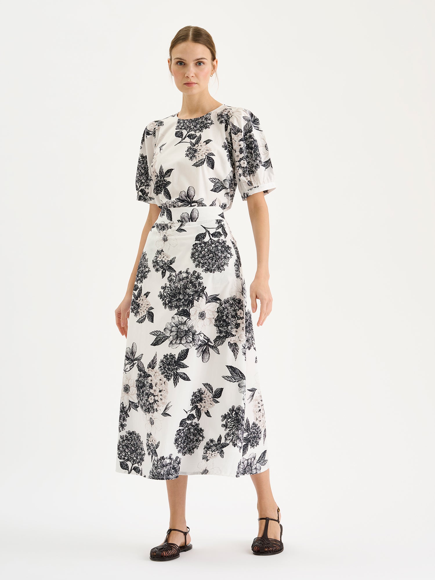 Nanso Palatsi blouse features a delicate floral pattern in black and white, pictured on a model with a matching skirt.