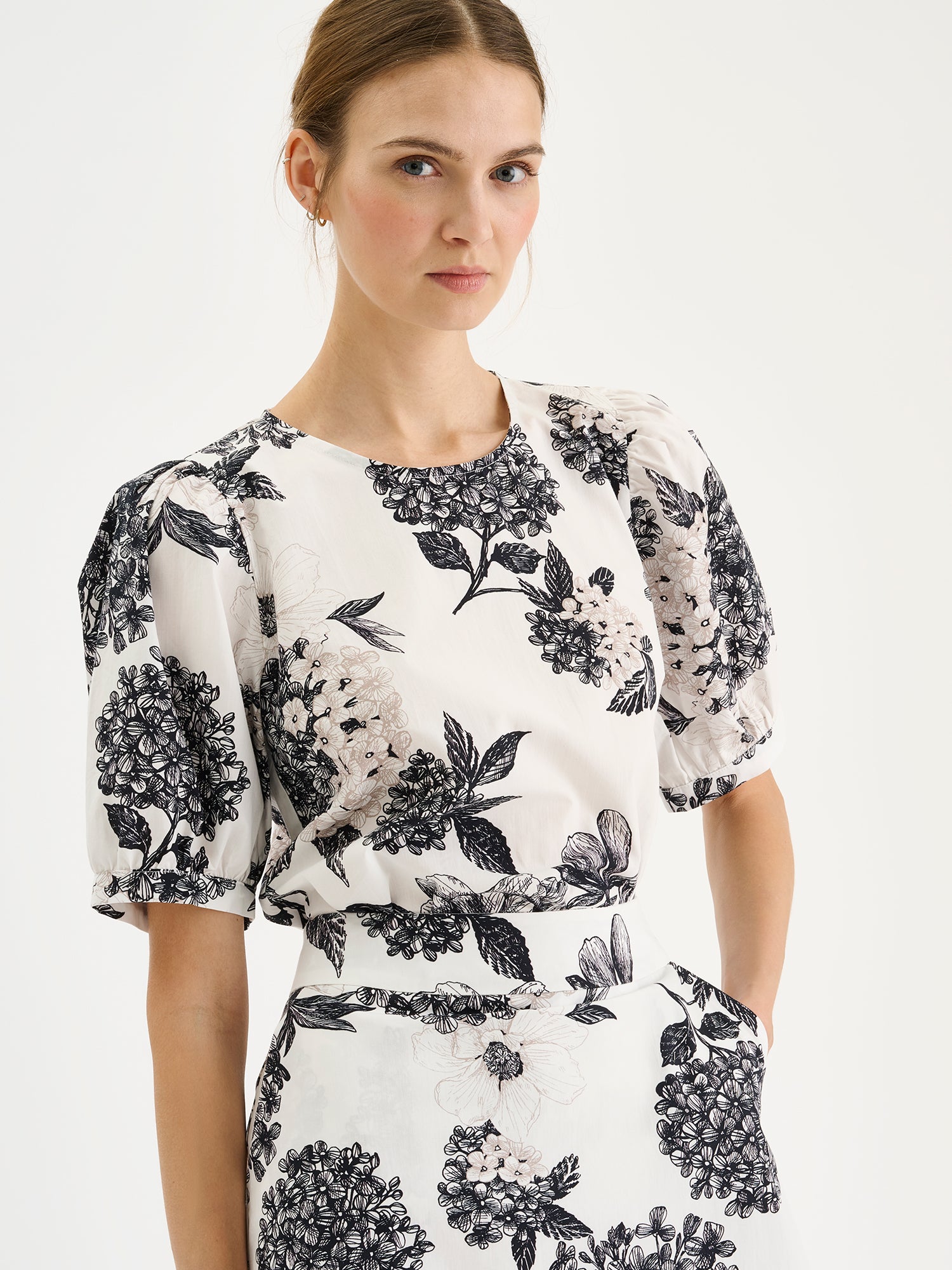 Nanso Palatsi blouse features a delicate floral pattern in black and white, pictured on a model with a matching skirt, close-up.