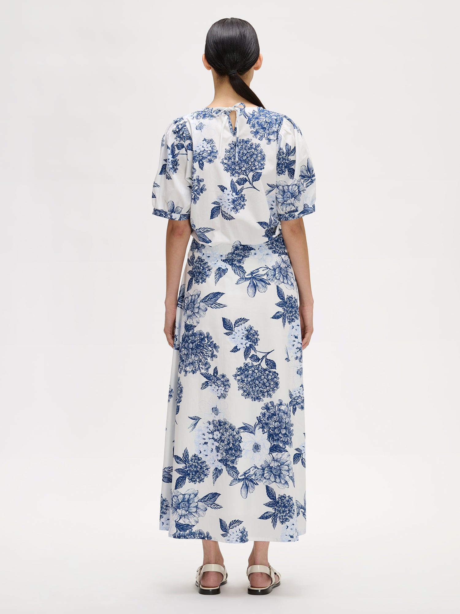 Nanso charming floral patterned Palatsi skirt, featuring a striking blue and white pattern on a model with a matching blouse, pictured from the backside