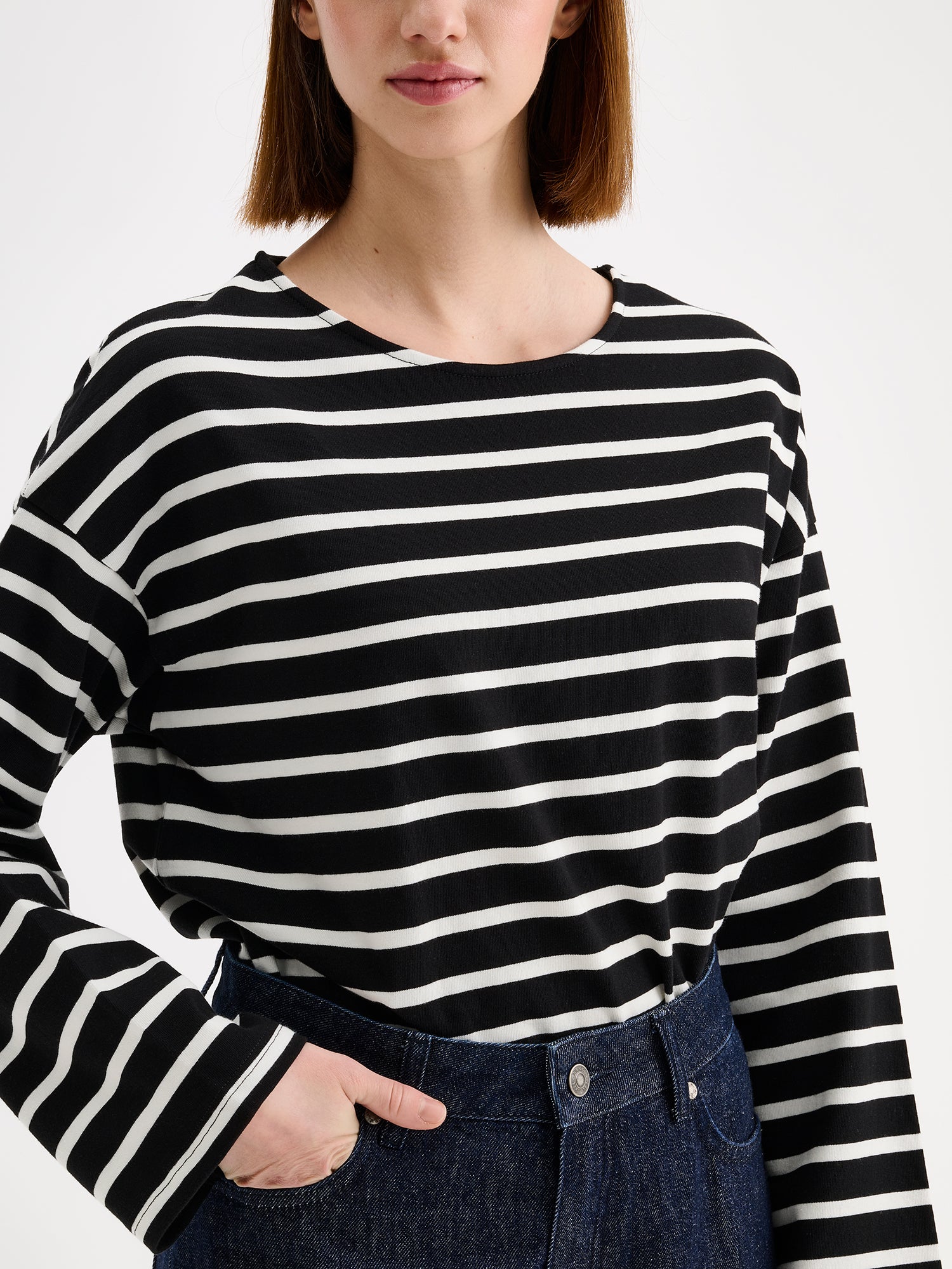 Nanso women's black and white striped long-sleeved Breton blouse with a relaxed, effortless fit, on a model with dark blue jeans, close-up.