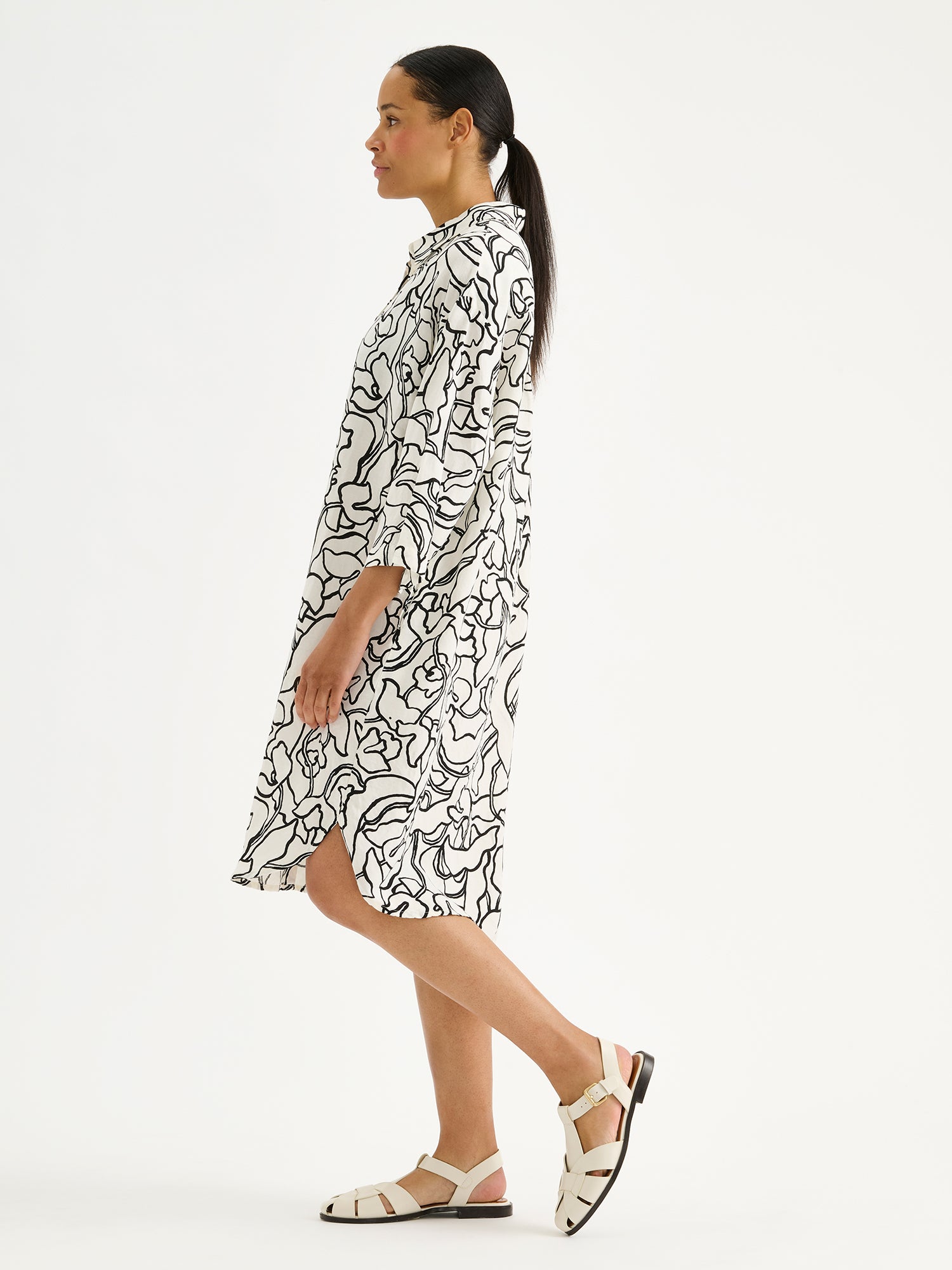 Nanso women's comfortable and relaxed Iiris shirt dress, featuring a striking black and white floral pattern on a model pictured from the side angle.