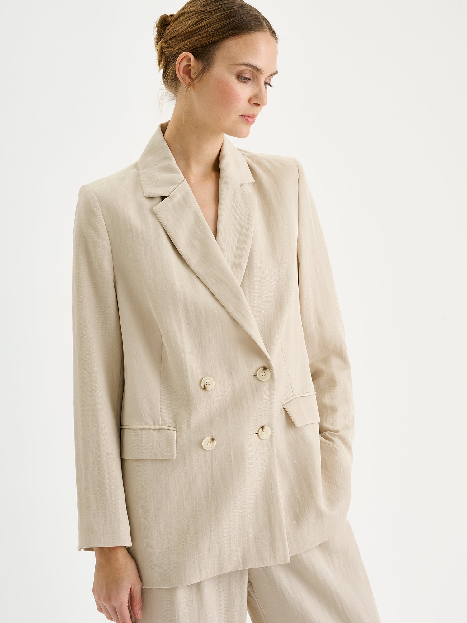 Nanso sophisticated beige blazer from the NIZZA collection on a model with matching trousers, close-up.