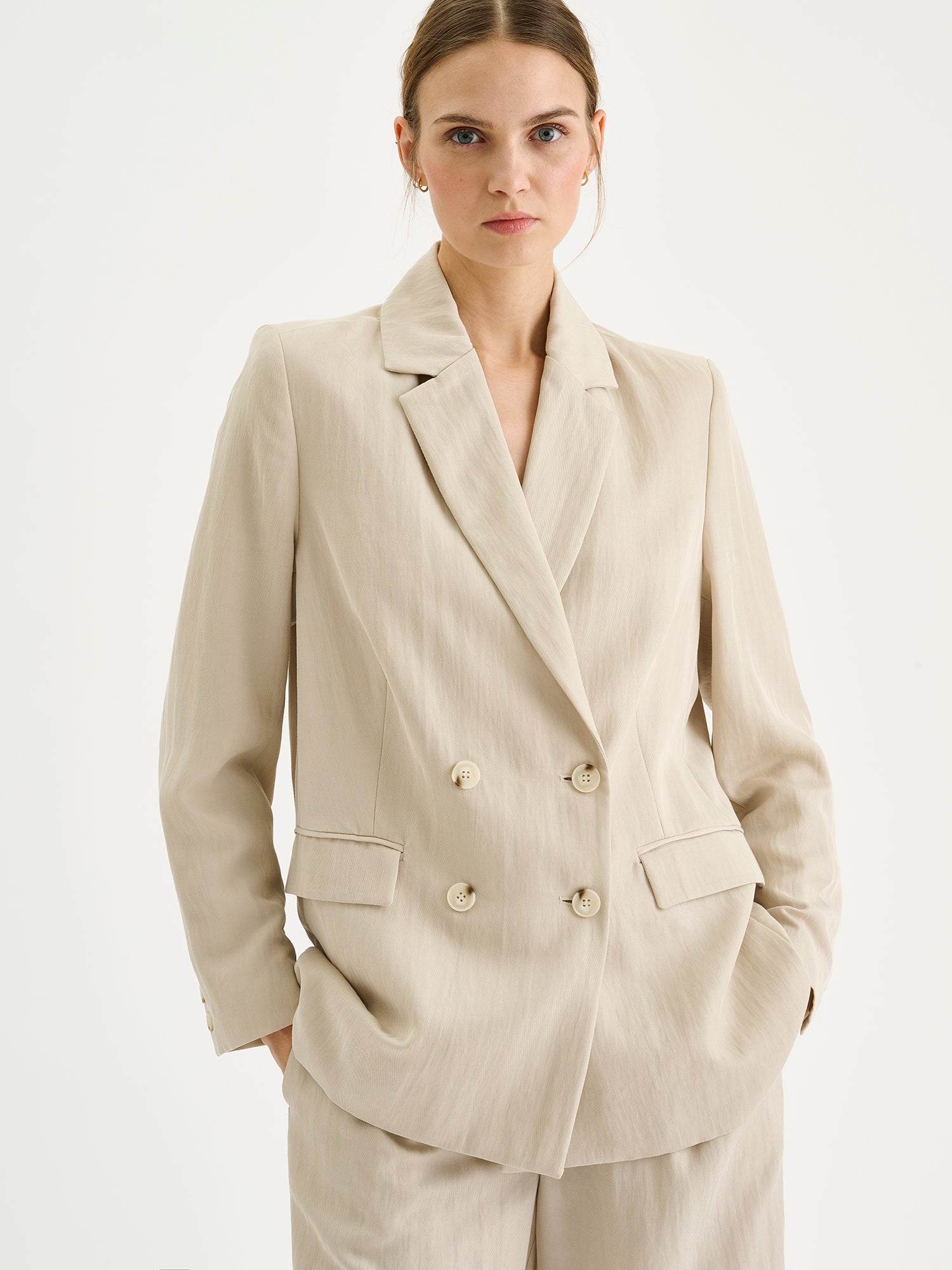 Nanso sophisticated beige blazer from the NIZZA collection on a model with matching trousers, close-up.