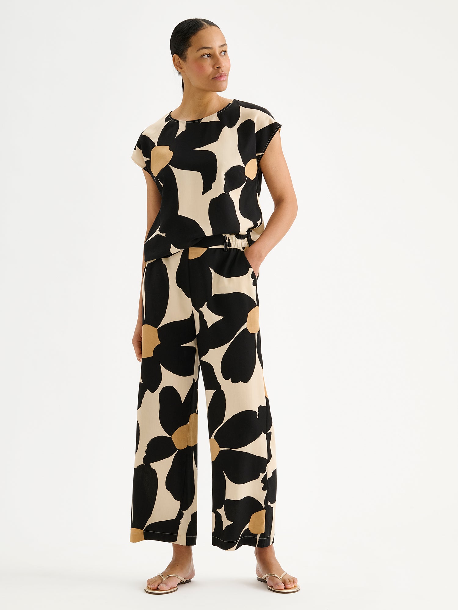 Nanso women's Rosi trousers feature a striking floral pattern and wide fit, pictured on a model with a matching blouse.