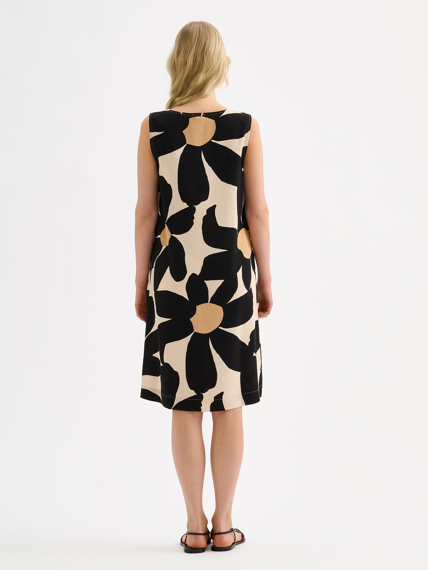 Nanso women's patterned sleeveless ROSI dress on a model with black sandals, pictured from the backside