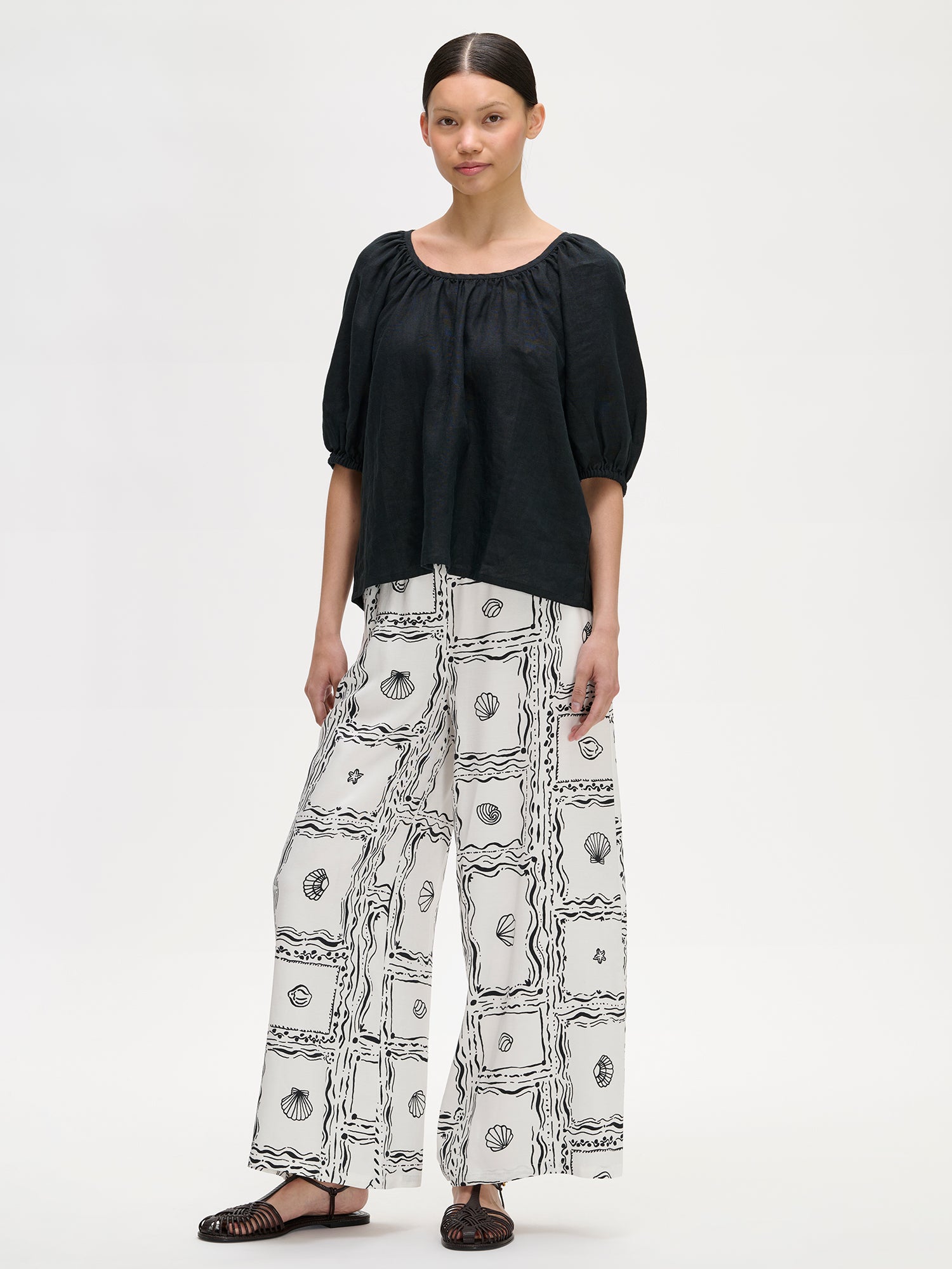 Nanso women's Donna linen blouse in black, on a model with wide patterned trousers.