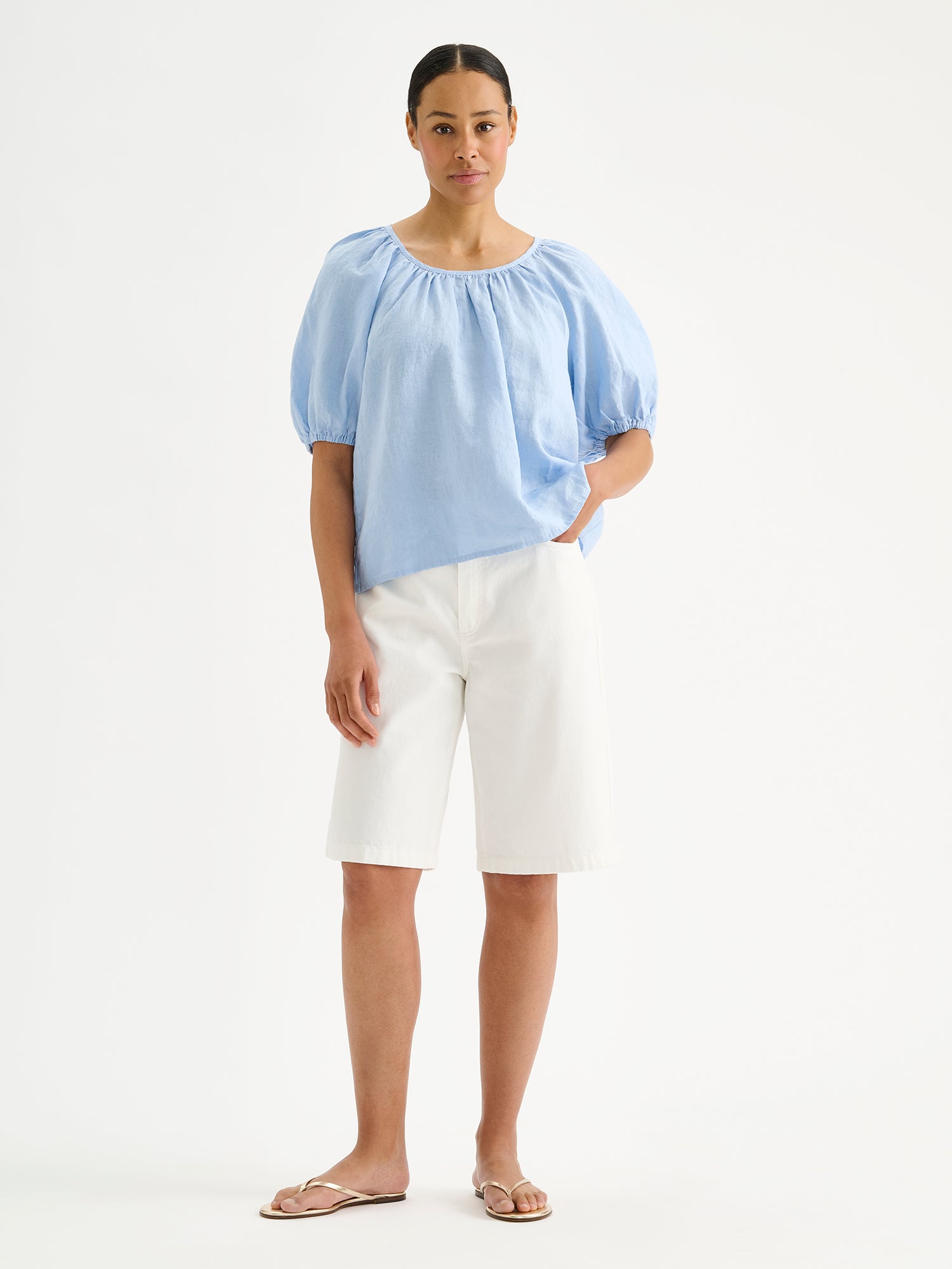 Nanso women's Donna linen blouse in a light blue shade on a model with white shorts and sandals