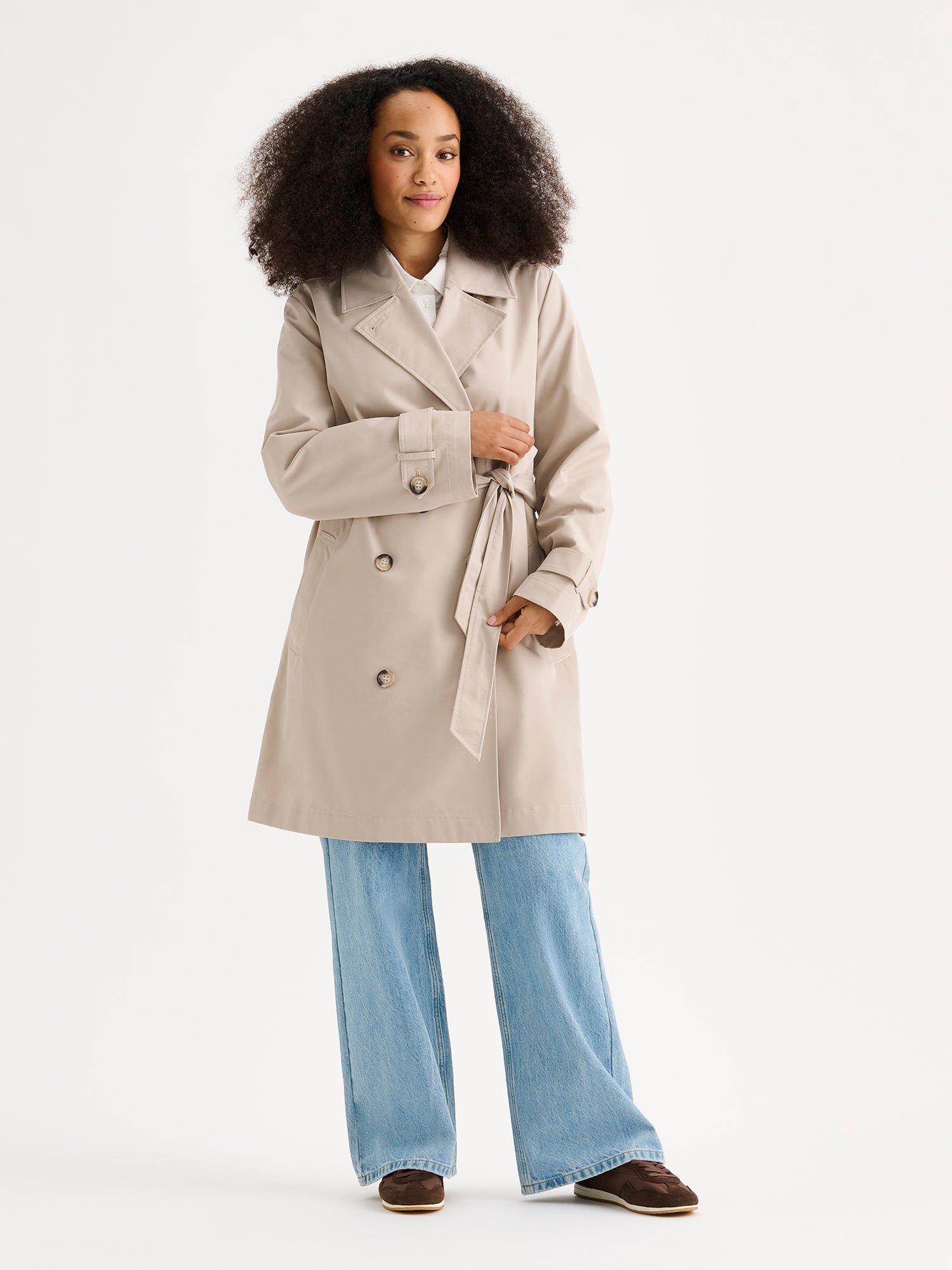 Nanso women's timeless midi trench coat in beige on a model with jeans.