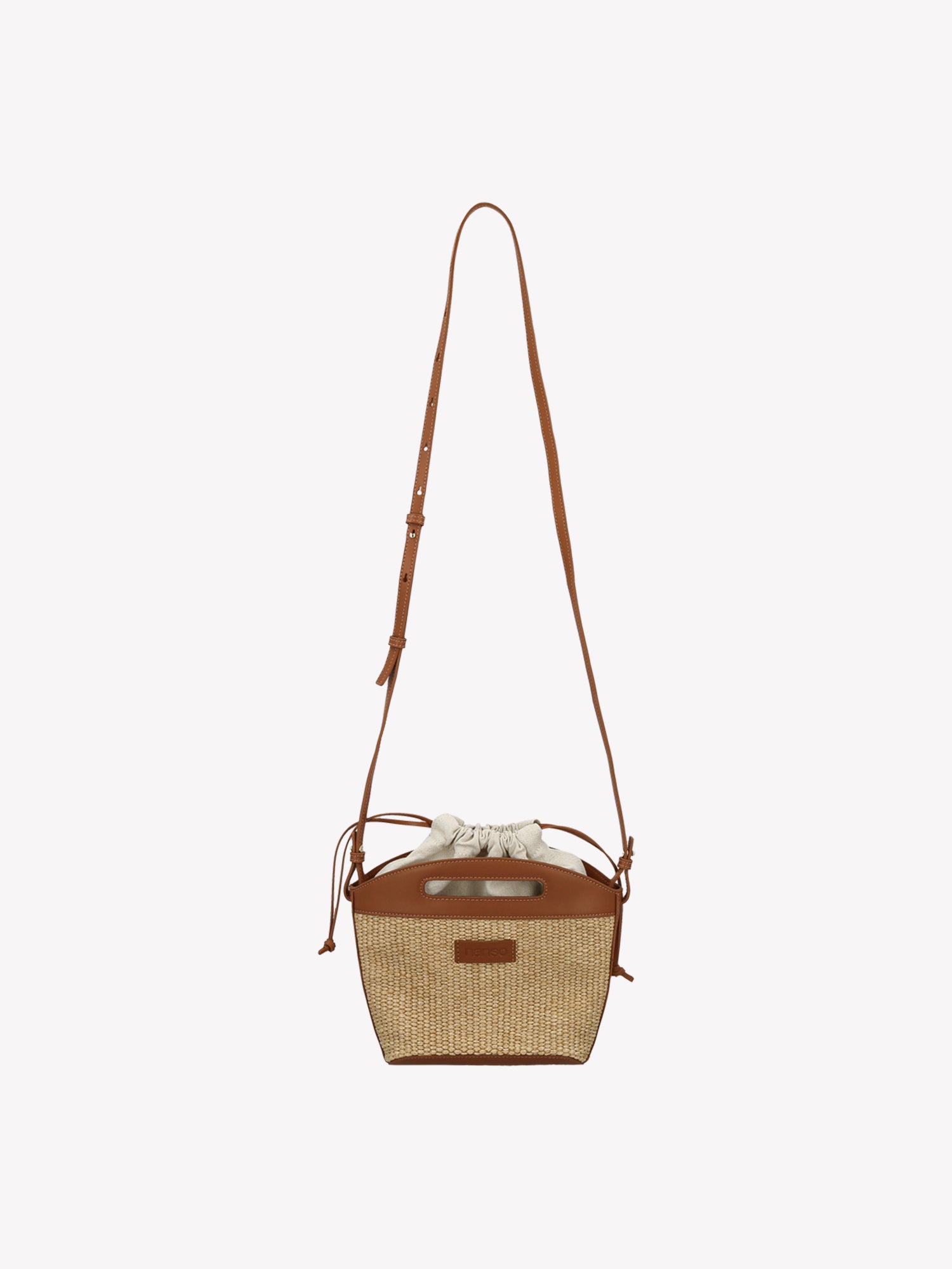 Crafted from durable straw-like material, the KORI Bag in Beige is a versatile cross body bag that is secured with elegant leather straps. Product picture from the front