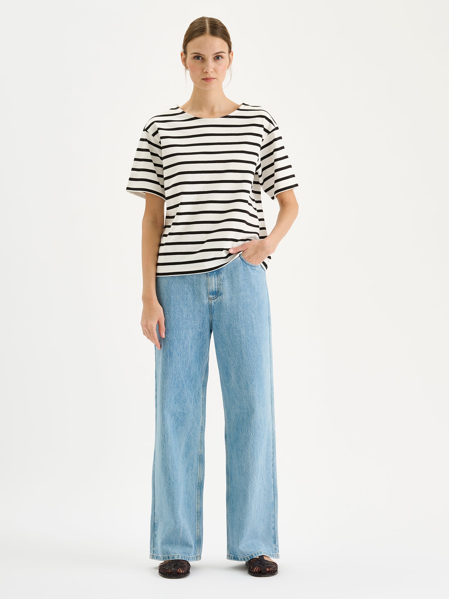 Nanso timeless black and white striped short-sleeved Breton T-shirt on a model with blue jeans.