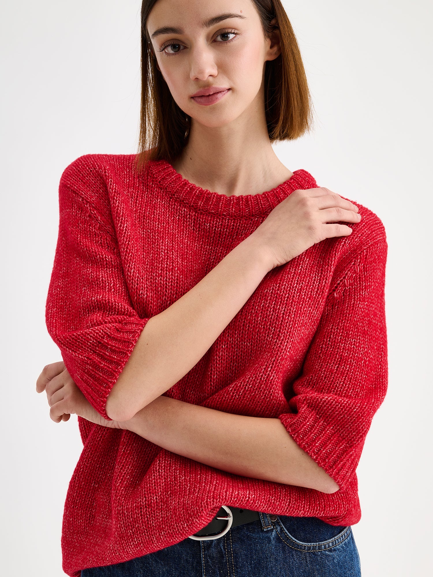 Nanso womens knit sweater Moriko in vibrant red, on a model with blue jeans, close-up.