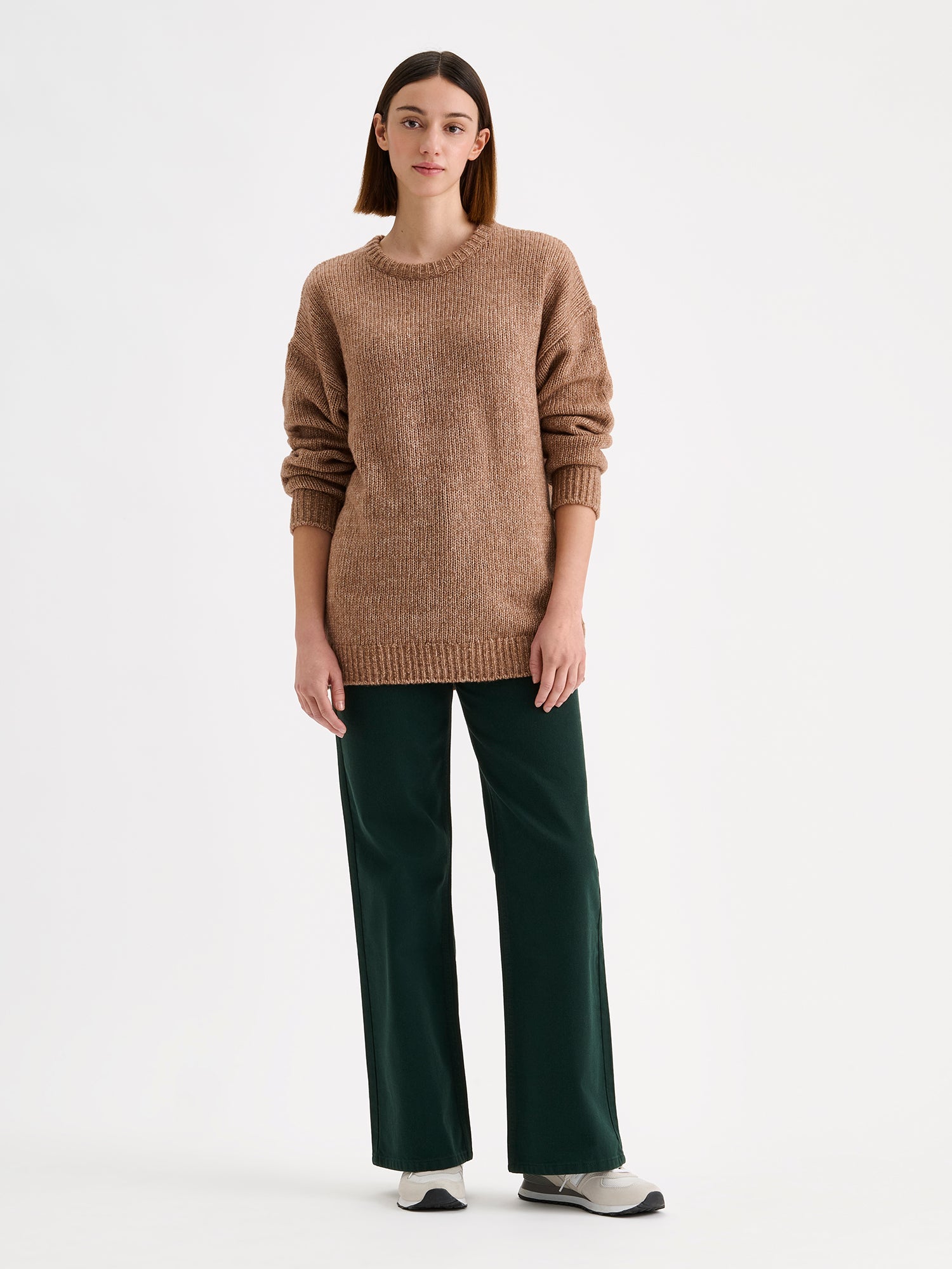 Women's relaxed long-sleeved MORIKO sweater in warm brown shade, on a model with dark green jeans.