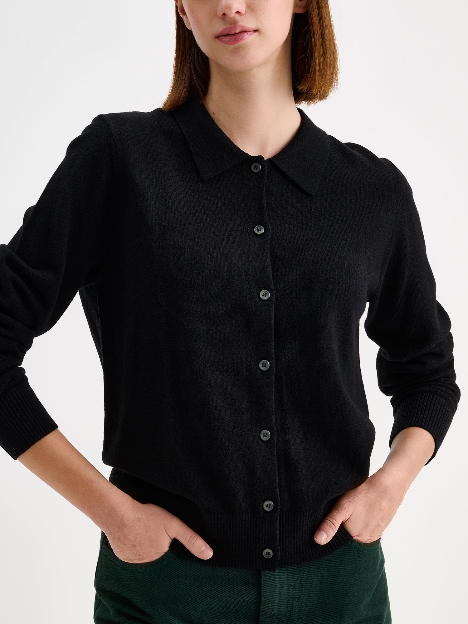 Nanso women's timeless black collared Villis cardigan on a model with dark green jeans