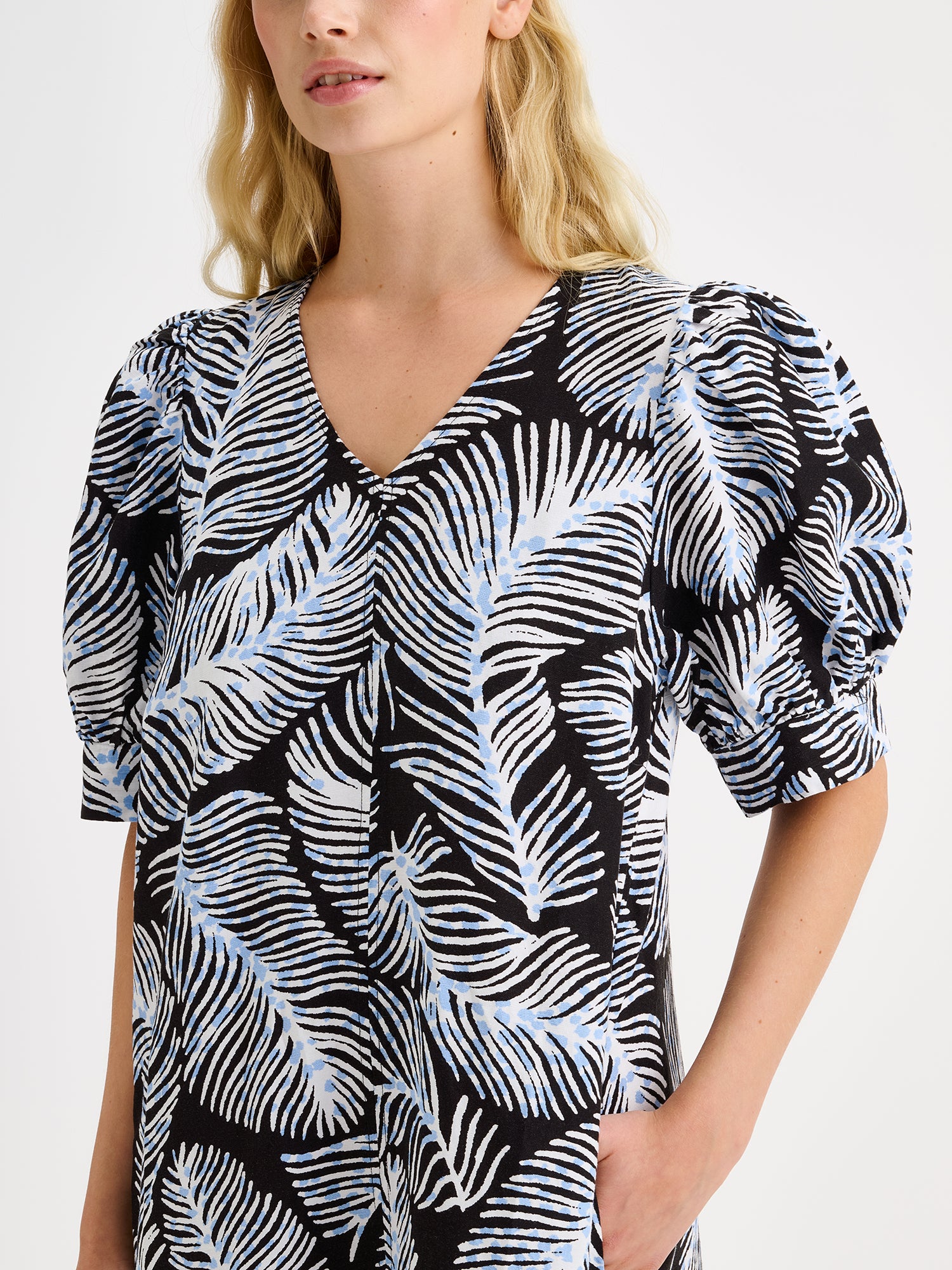 Nanso women's midi Hilde dress in a stylish and delicate black and blue-white print on a blonde model, close-up.