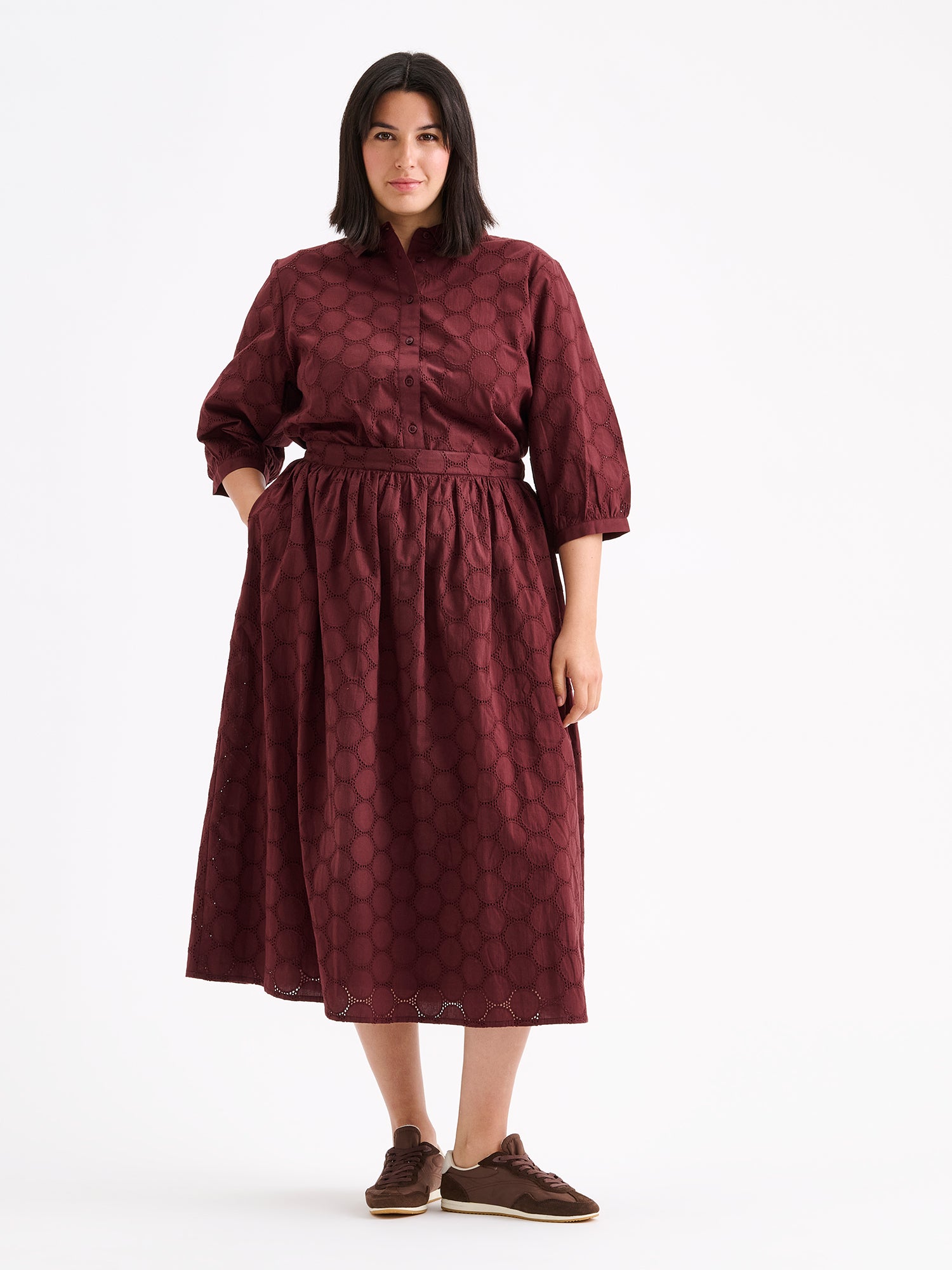 nanso women's stylish dark brown Siiri blouse for women, featuring beautiful embroidered fabric, classic collar, buttons and 3/4 sleeves, on a model with a matching skirt.
