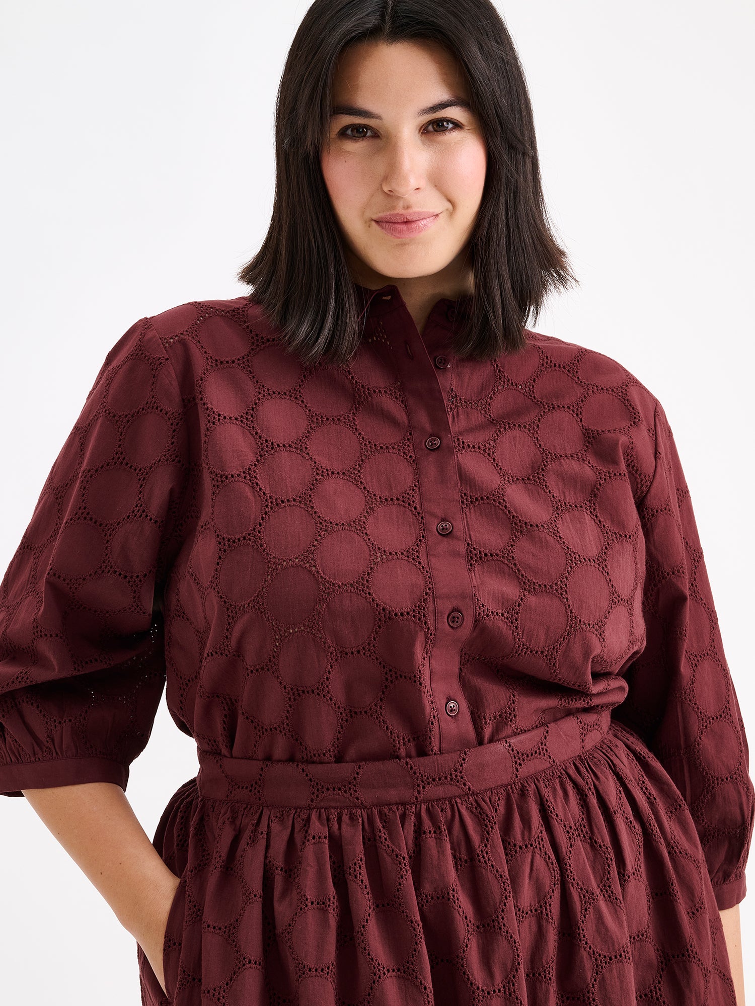 nanso women's stylish dark brown Siiri blouse for women, featuring beautiful embroidered fabric, classic collar, buttons and 3/4 sleeves, on a model with a matching skirt, close-up.