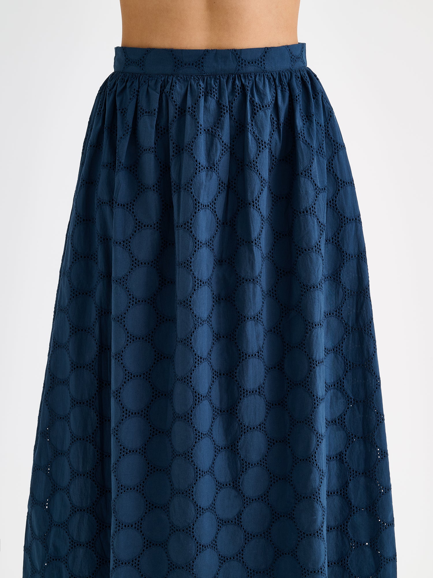 Nanso women's dark blue Siiri midi skirt, featuring a delicate lace-like woven cotton fabric with beautiful texture, pockets and a zip, on a model, close-up.