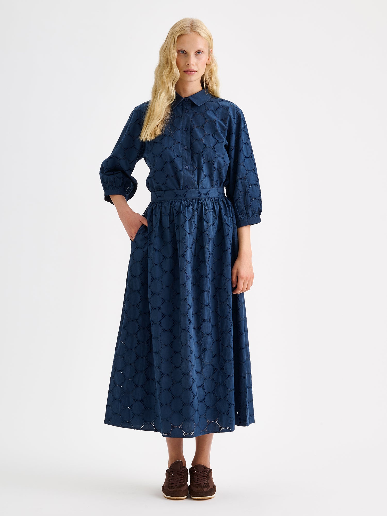 Nanso women's dark blue Siiri midi skirt, featuring a delicate lace-like woven cotton fabric with beautiful texture, pockets and a zip, on a model with a matching blouse.