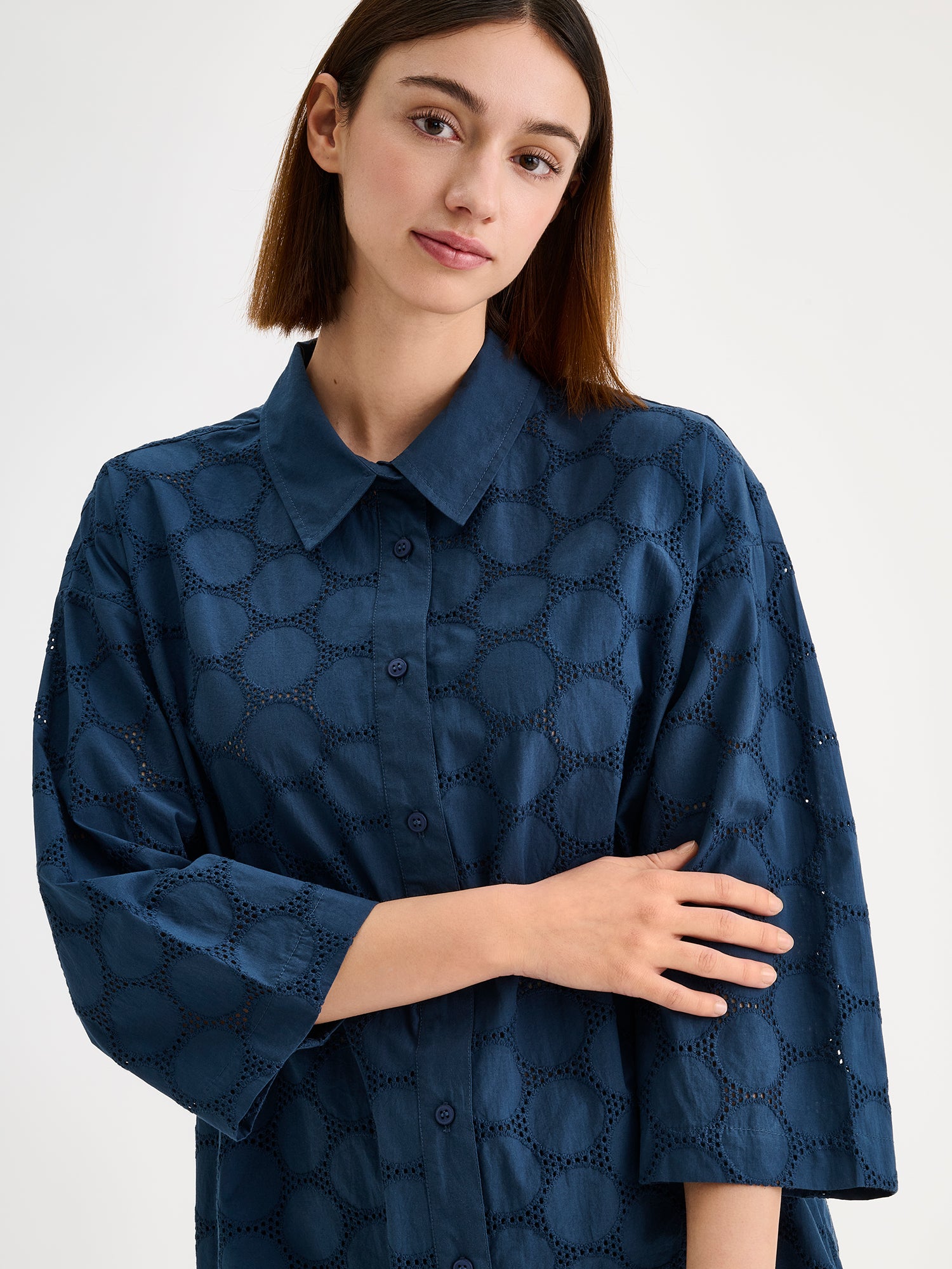 Nanso women's SIIRI Long Shirt in blue is a relaxed-fit women's shirt with an elegant embroidered lace-like pattern, classic collar and buttons, on a model close-up.