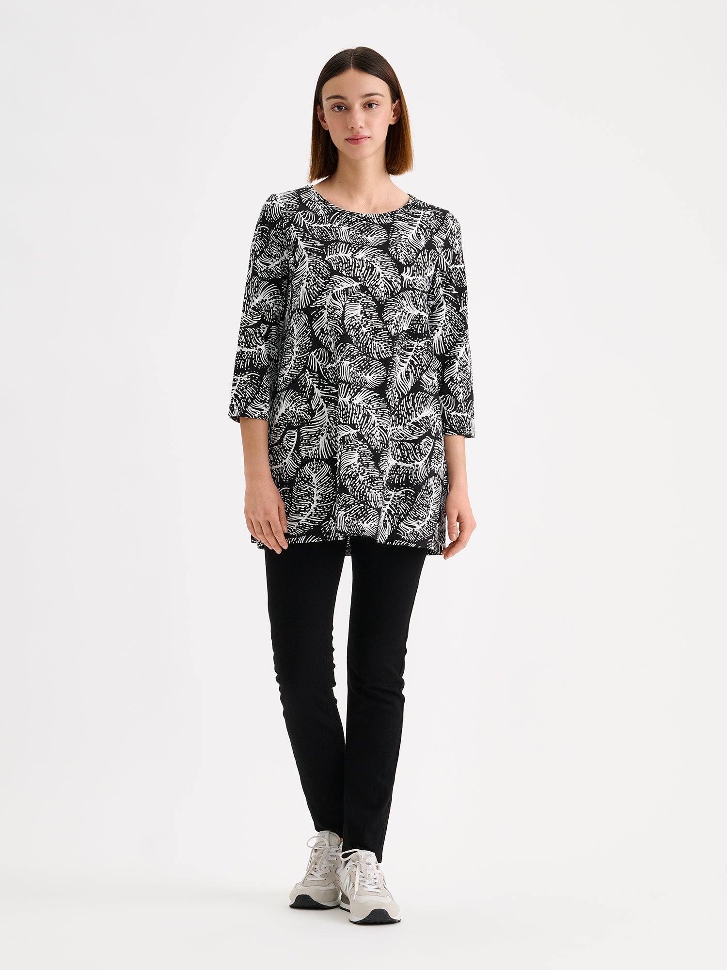 Nanso Women's Pieni Hilde Jersey Tunic in black and white, is a comfortable and beautiful everyday essential. Pictured on a model with black trousers and sneakers.
