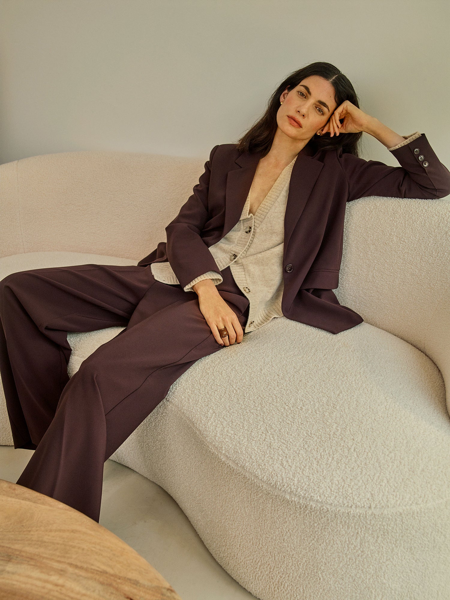 A stylish women's Eeva blazer in a rich brown shade with a relaxed yet structured silhouette, on a model with a beige knitted cardigan