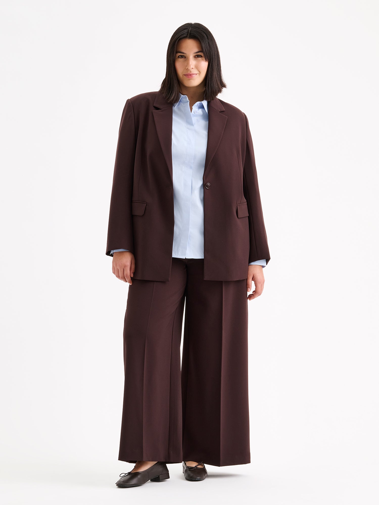 A stylish women's Eeva blazer in a rich brown shade with a relaxed yet structured silhouette, on a model with a light blue shirt and ballerinas | 46 - 178cm