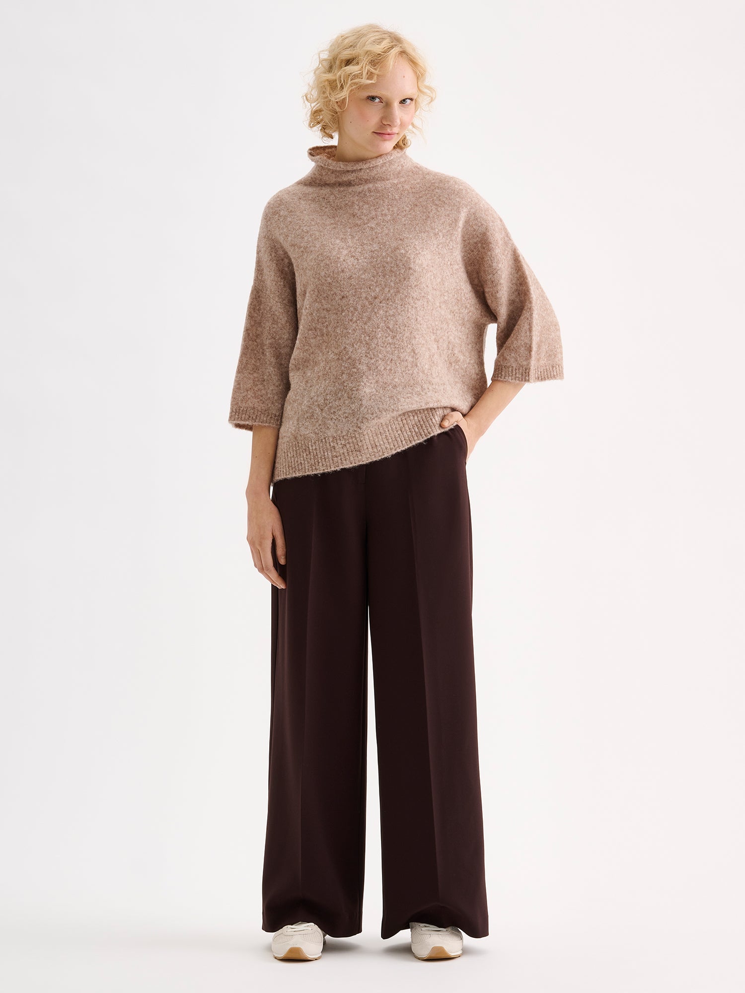 Nanso women's relaxed Alina knit sweater with a high neckline on a model with brown trousers | S - 177cm
