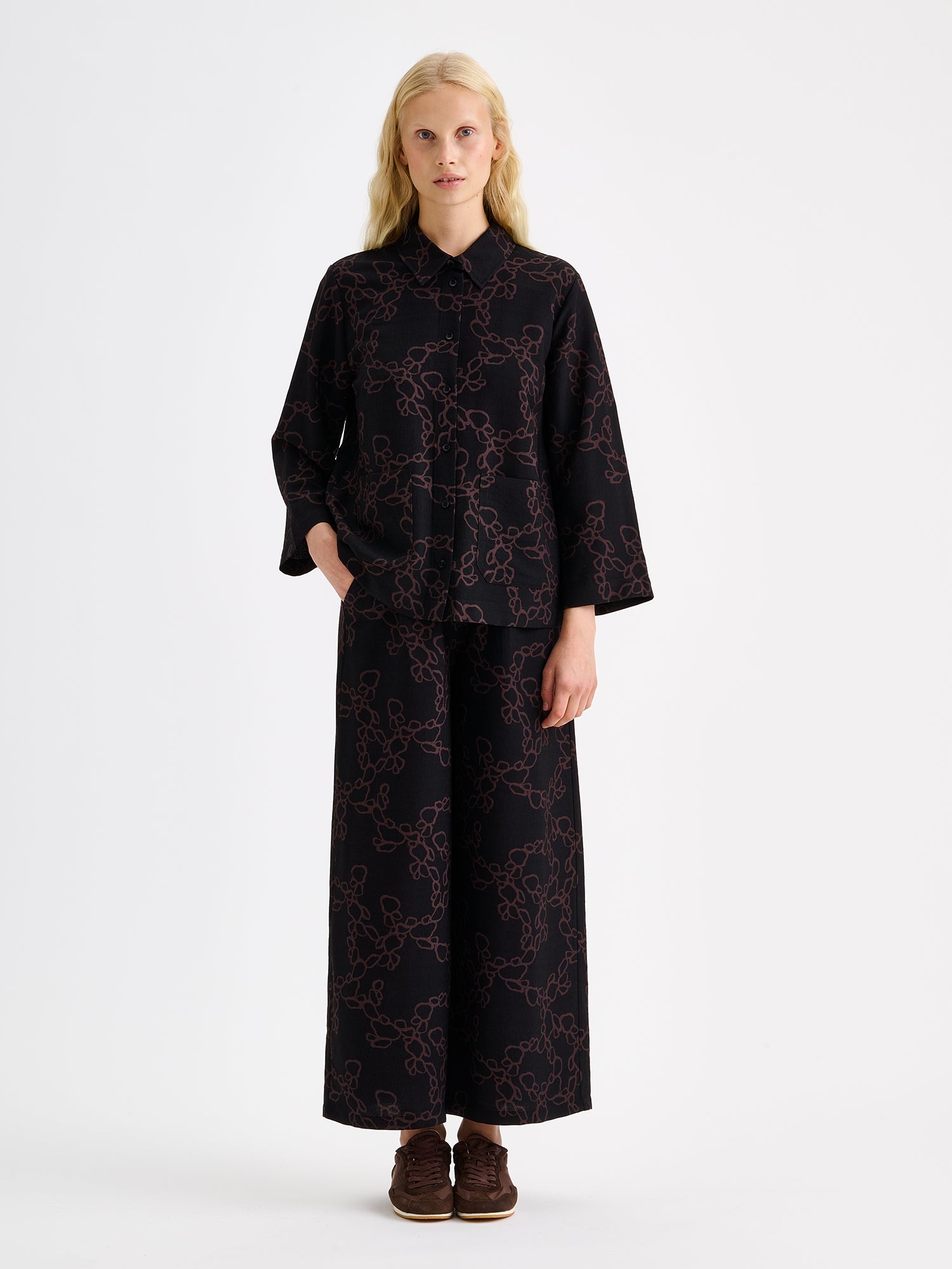 Women's patterned black and brown KIDE shirt and wide trousers on a model