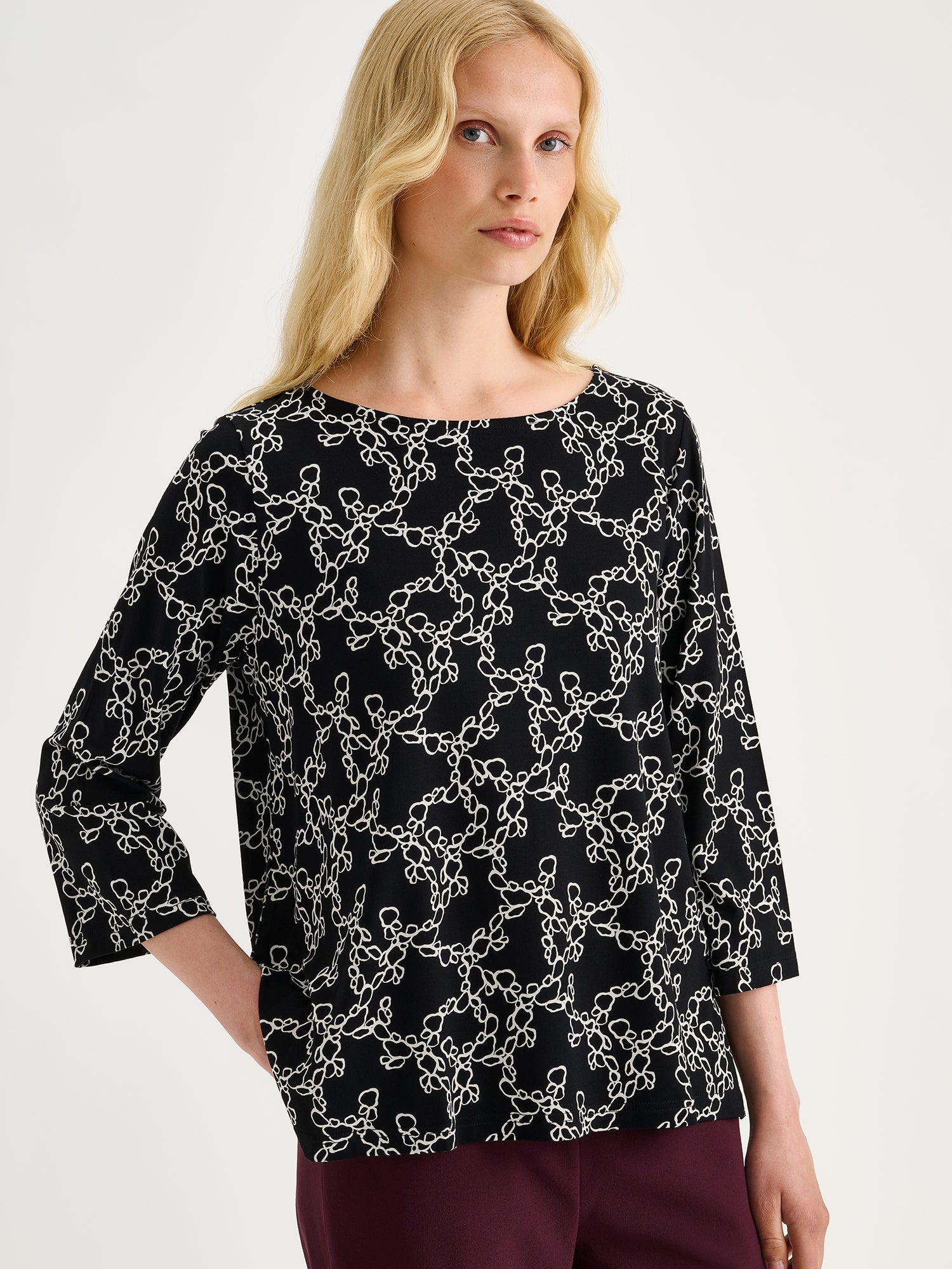 Women's patterned black and white Pieni Kide jersey blouse on a blonde model with winered trousers | S - 174cm