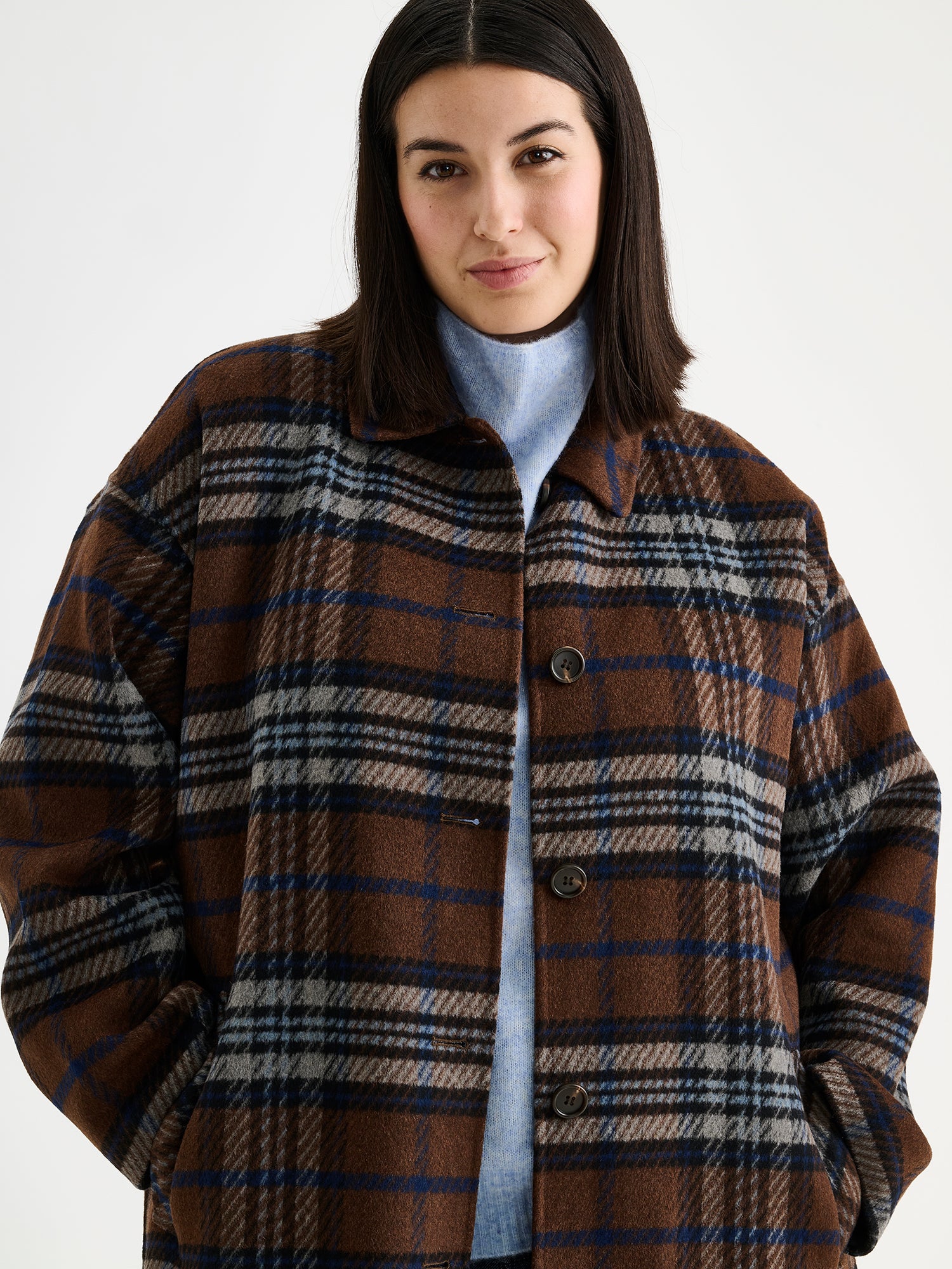 The stylish and timeless Astrid wool coat features a contemporary checked pattern, pictured on a model, close-up
