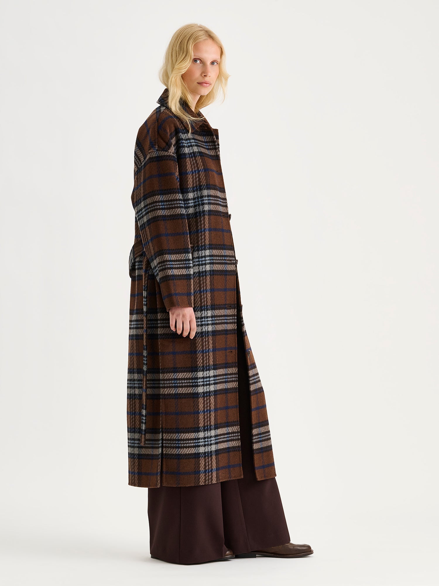 The stylish and timeless Astrid wool coat features a contemporary checked pattern, pictured on a model, from the side