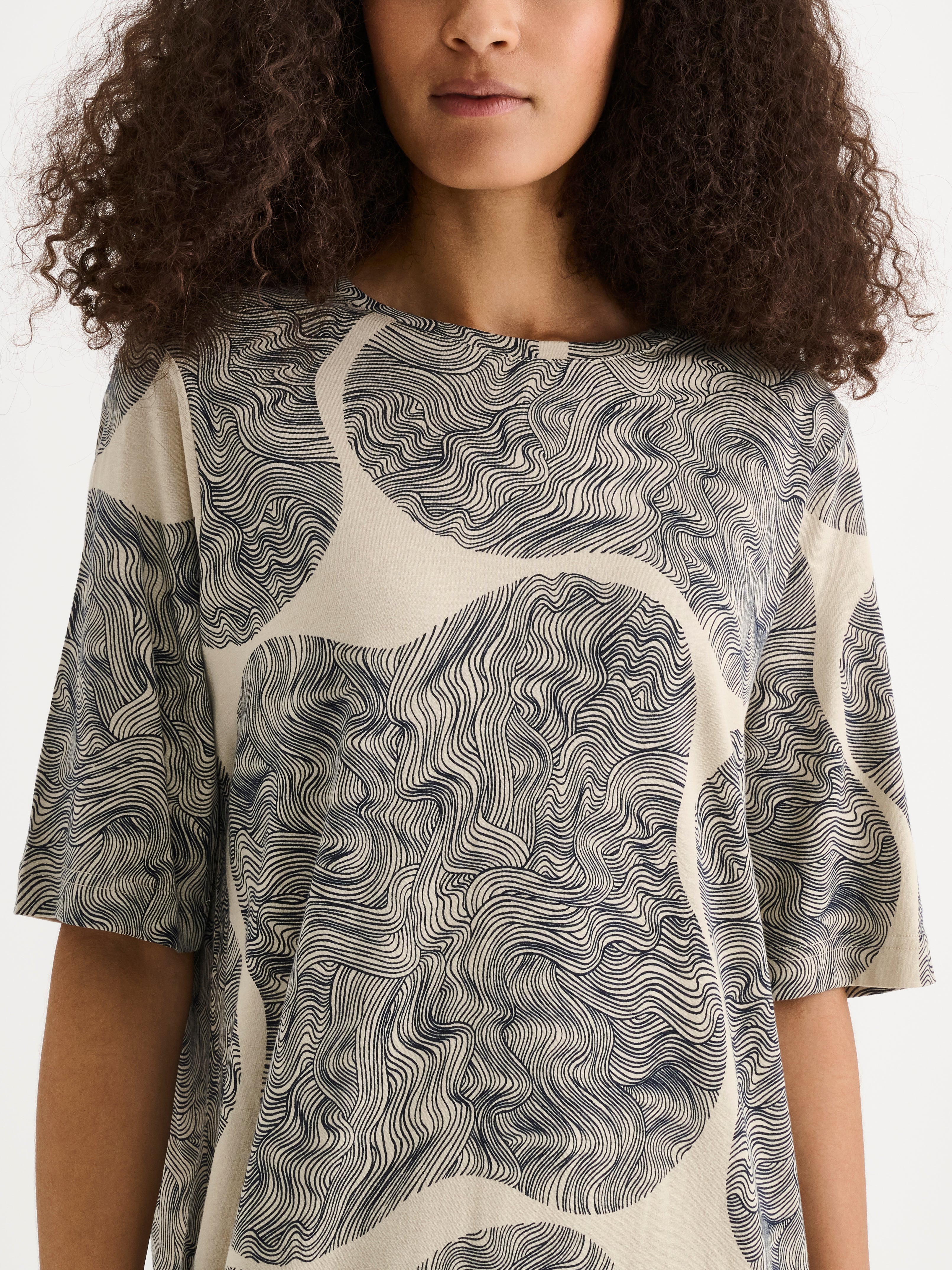 The relaxed, straight-cut Paasi nightdress for women with a harmonious beige-toned print, on a model close-up.