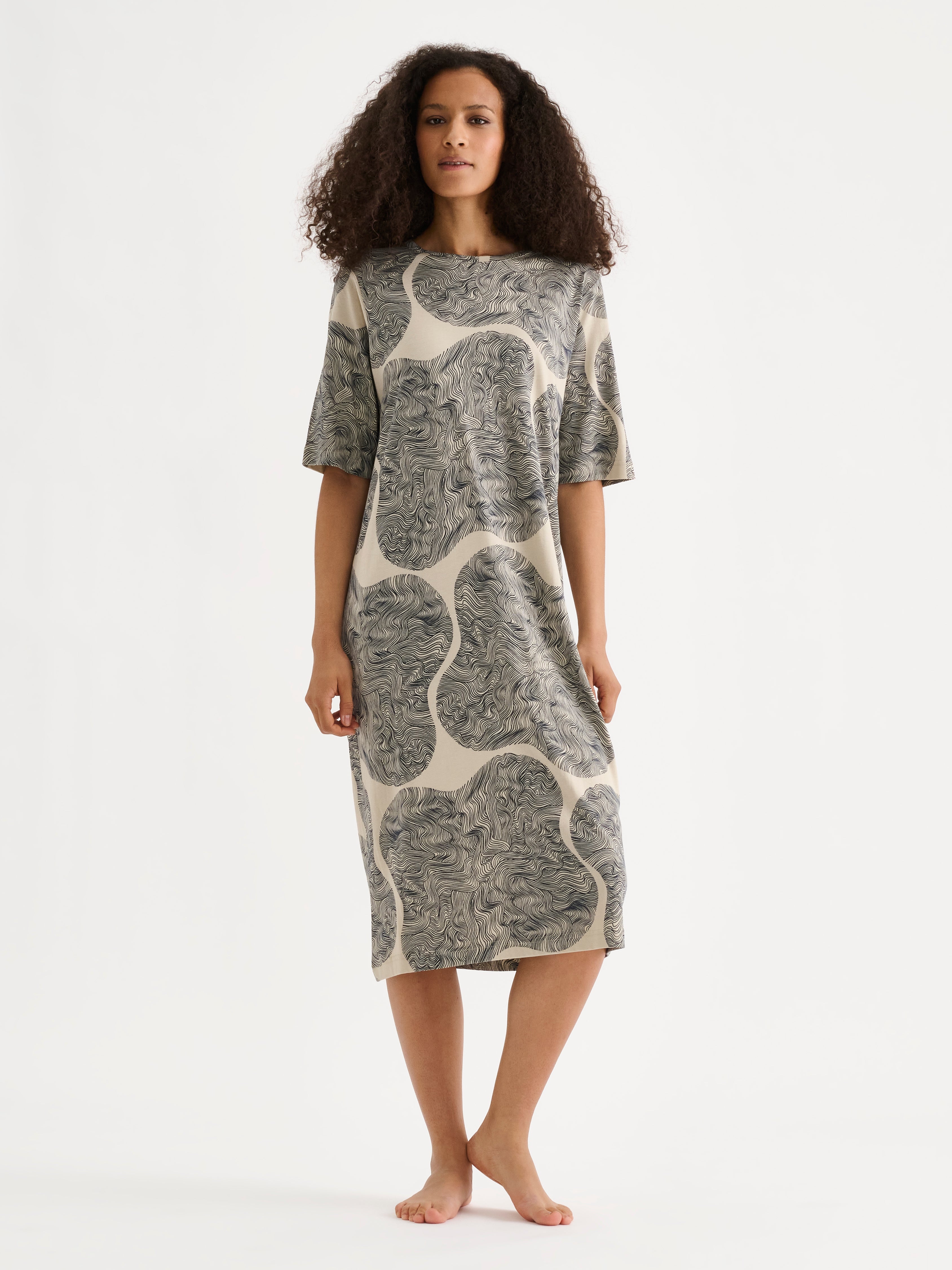 The relaxed, straight-cut Paasi nightdress for women with a harmonious beige-toned print, on a model.
