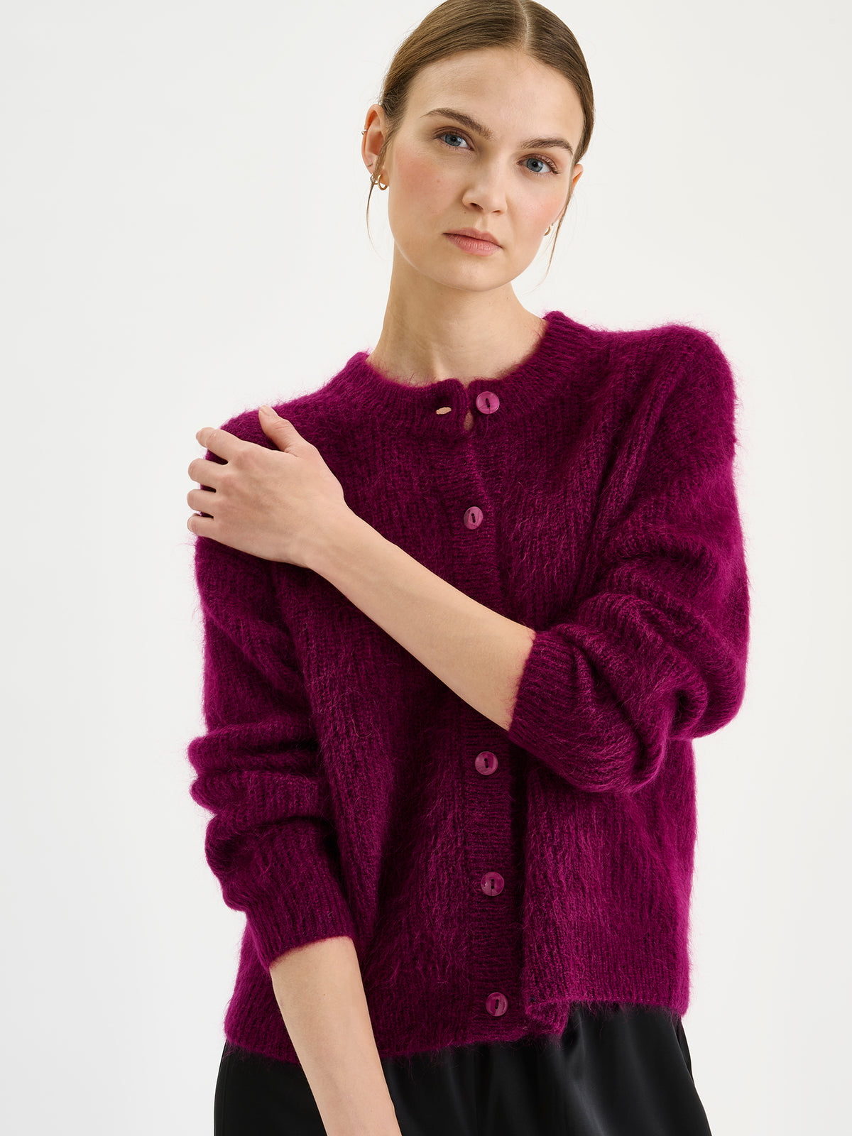 Nanso women's wonderfully warm and luxurious Sumi cardigan enchants with its vibrant violet hue and beautifully fluffy texture, pictured on a model with black trousers.