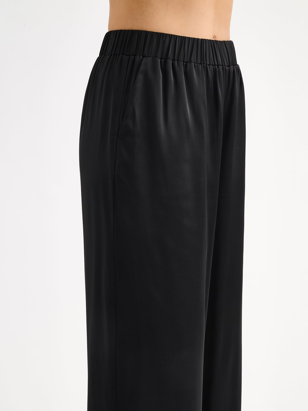 Nanso women's elegant Silva satin trousers captivate with their classic black and beautifully flowing satin fabric, pictured on a model close-up.