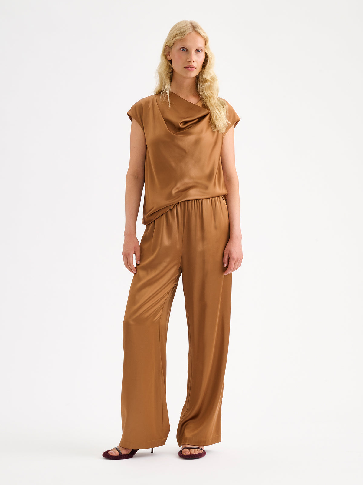 Nanso women's elegant Silva satin trousers captivate with their rich brown shade and beautifully flowing satin fabric. On a model with a matching blouse.