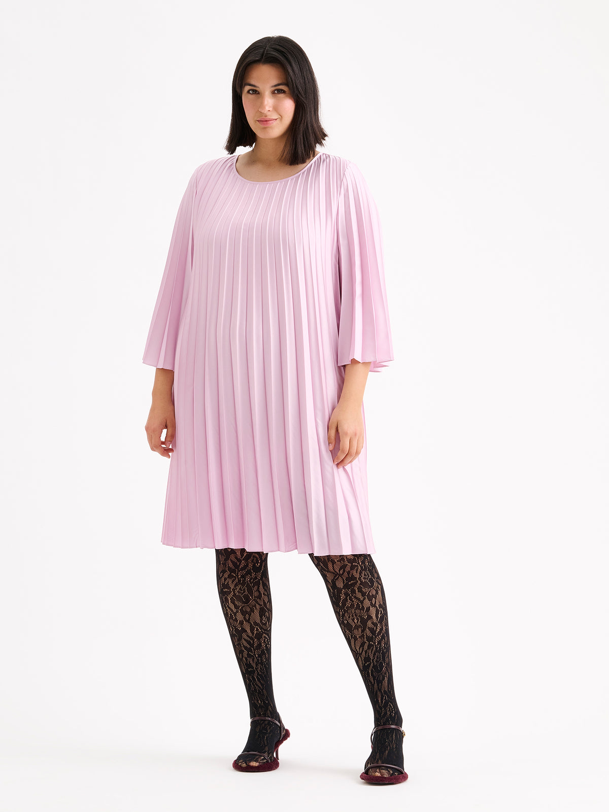 Nanso women's beautifully draping Taite dress in a deliciously cool light pink shade. This versatile pleated dress can be worn with or without the slim belt. This A-line dress features 3/4-length sleeves and a slim belt at the waist. Pictured on a model with heels without the belt.