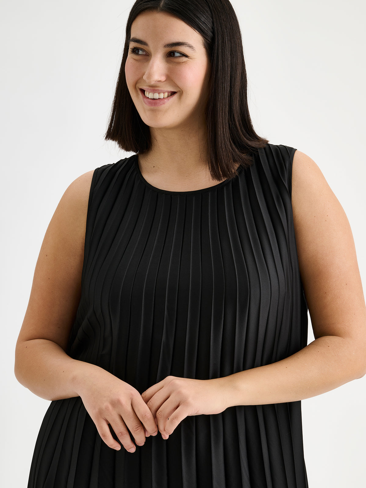 Nanso women's beautifully draping long Taite dress in a classic black shade. This long, sleeveless pleated dress with a slim belt is a striking choice for festive occasions and other special moments throughout the season. Pictured on a model close-up.