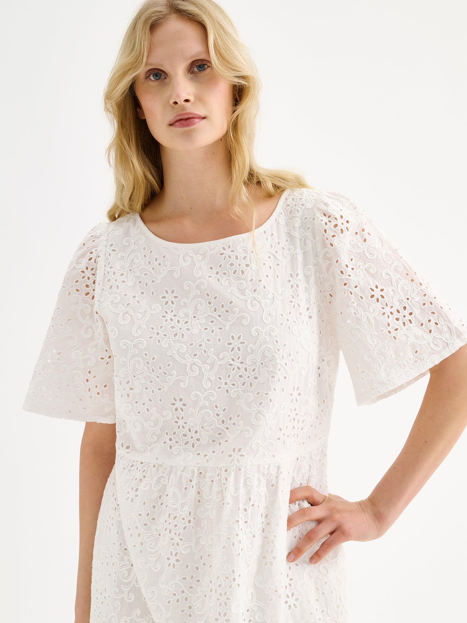 Nanso women's beautiful long soft white Odette dress crafted from delicate broderie anglaise style cotton fabric with a lace-like texture on a model, close-up