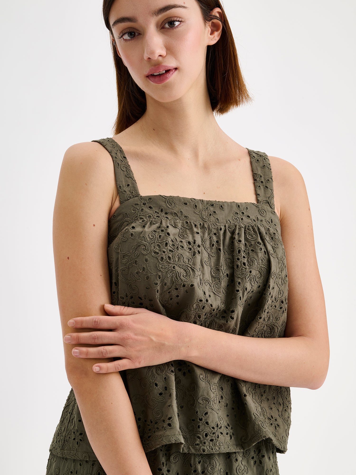 Nanso women's beautiful olive green Odette top for women, crafted from delicate lace-like Broderie anglaise style cotton fabric, on a model with a matching skirt, close-up.