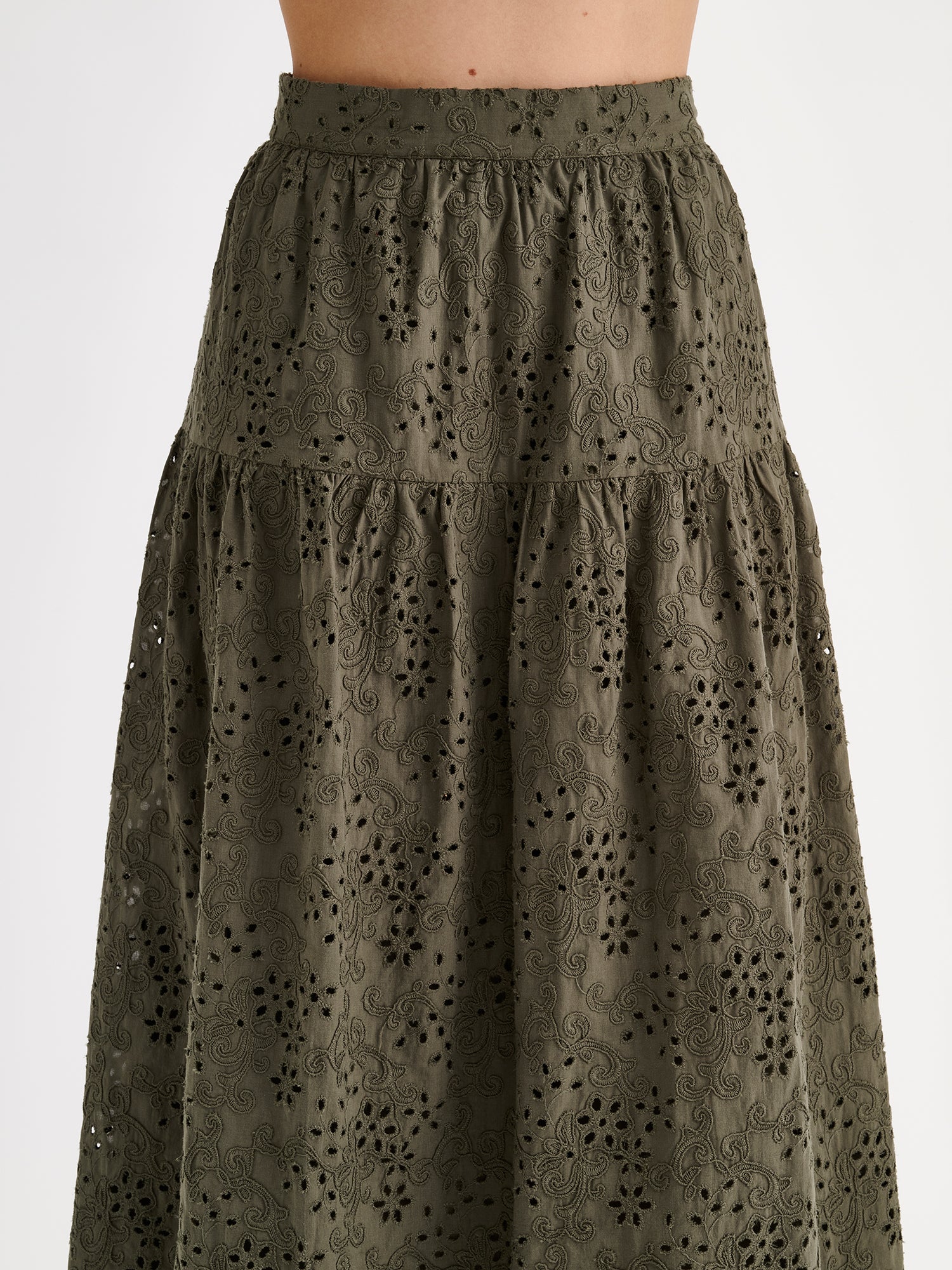 Nanso women's Odette skirt is a beautiful maxi-length skirt with a flowing silhouette, crafted from olive green cotton fabric featuring delicate broderie anglaise detailing, on a model close-up.